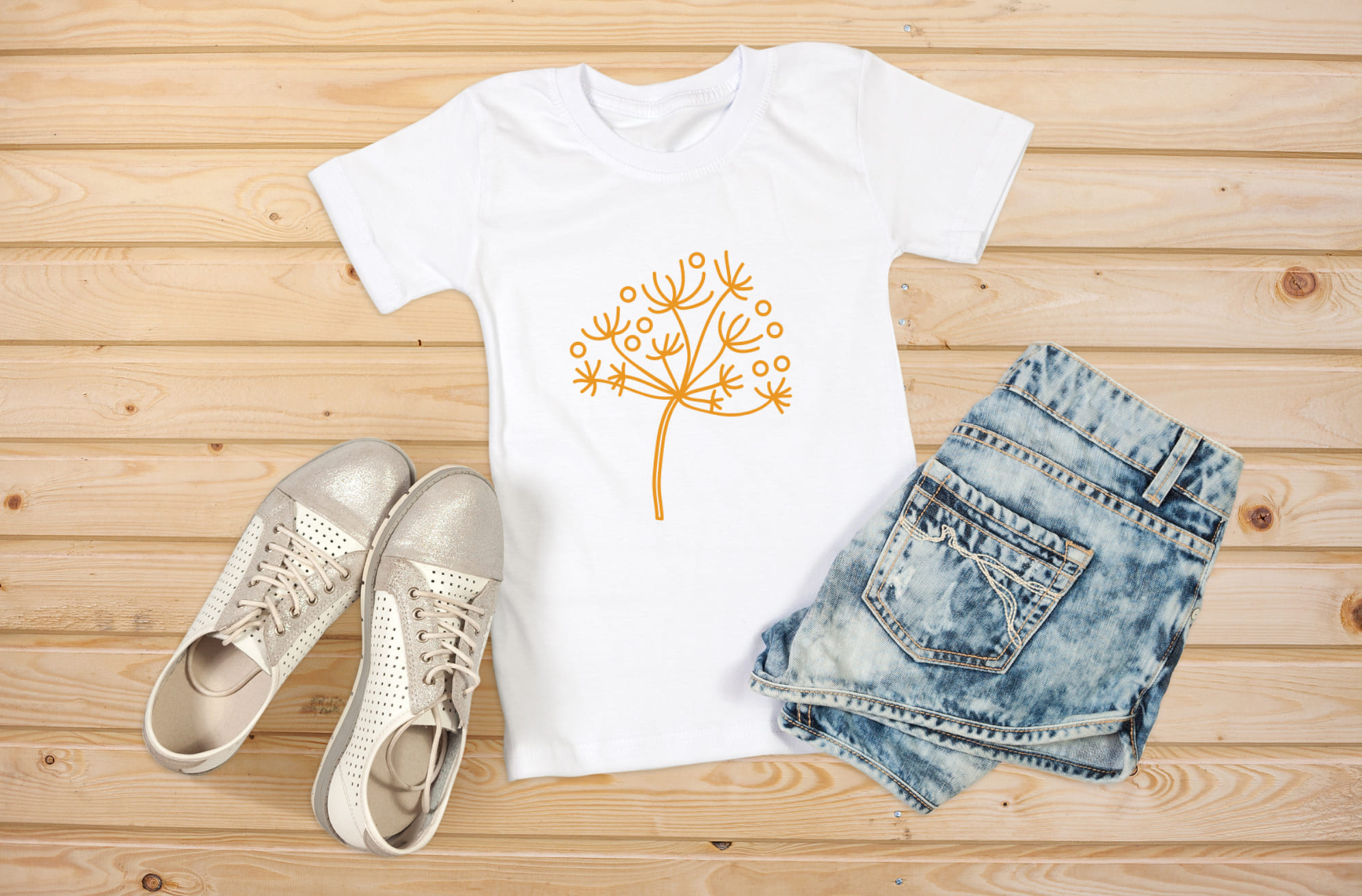 Image of t-shirt with colorful dandelion print in orange.