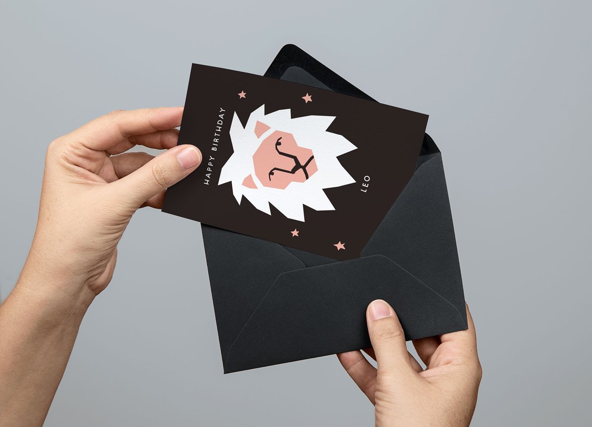 Black greeting card with a black envelope held by a hand on a gray background.