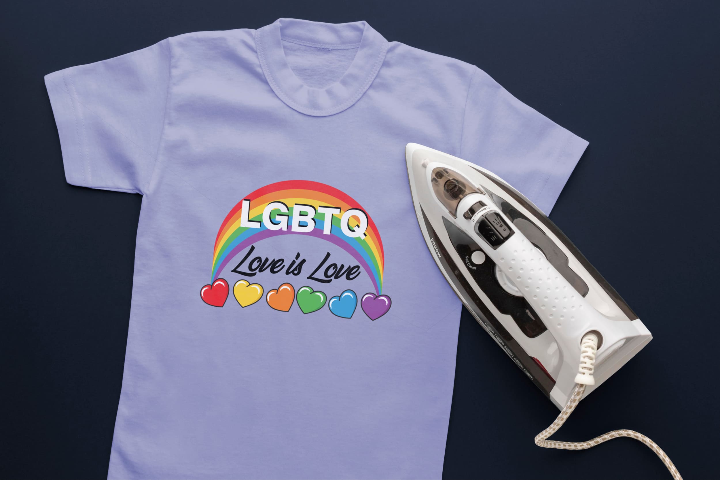 Light blue t-shirt with LGBT rainbow, white and black lettering "LGBT love is love", hearts in LGBT colors and an iron.