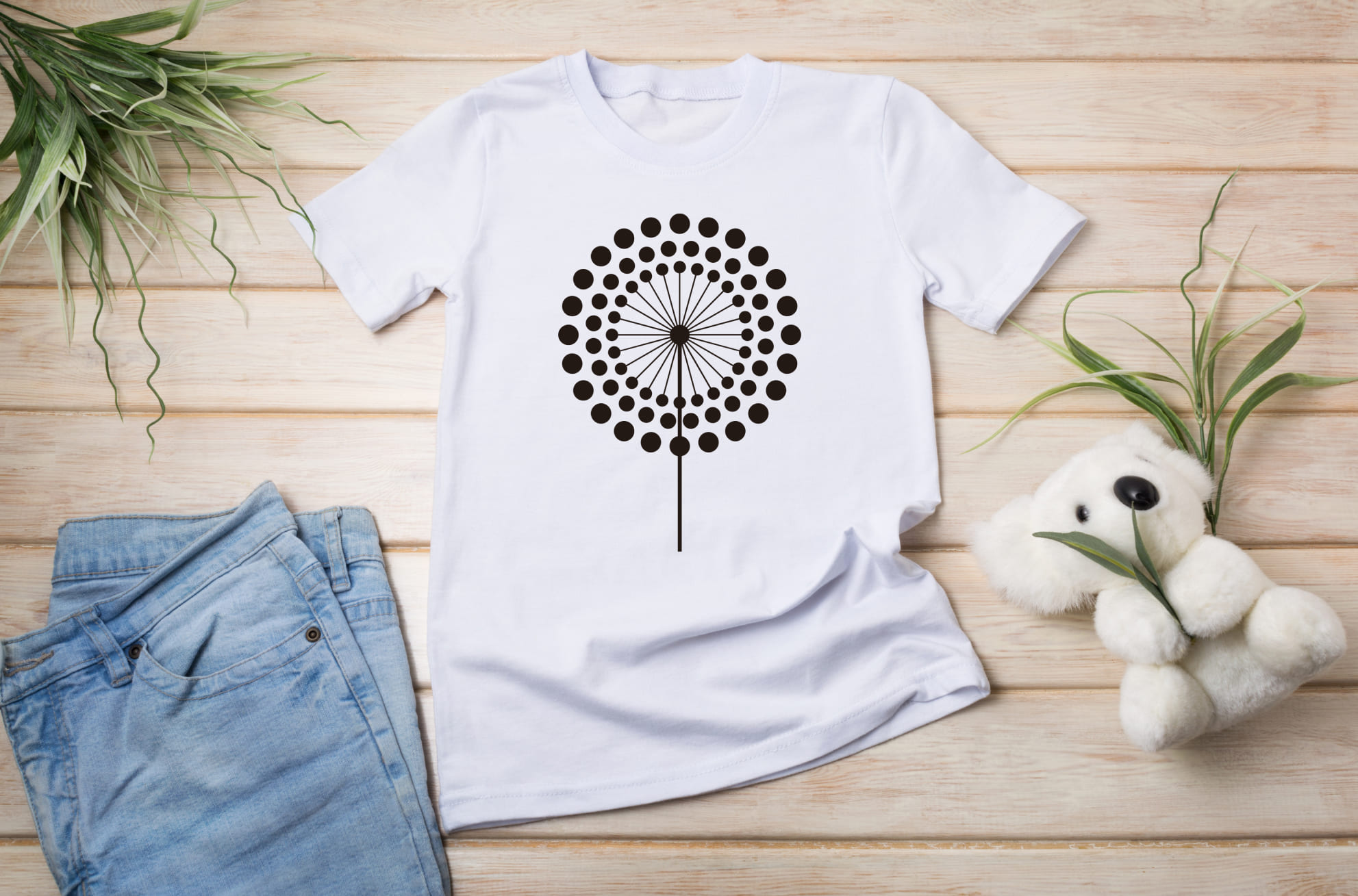 A white T-shirt with a black minimalistic dandelion flower and jeans with a white toy koala.