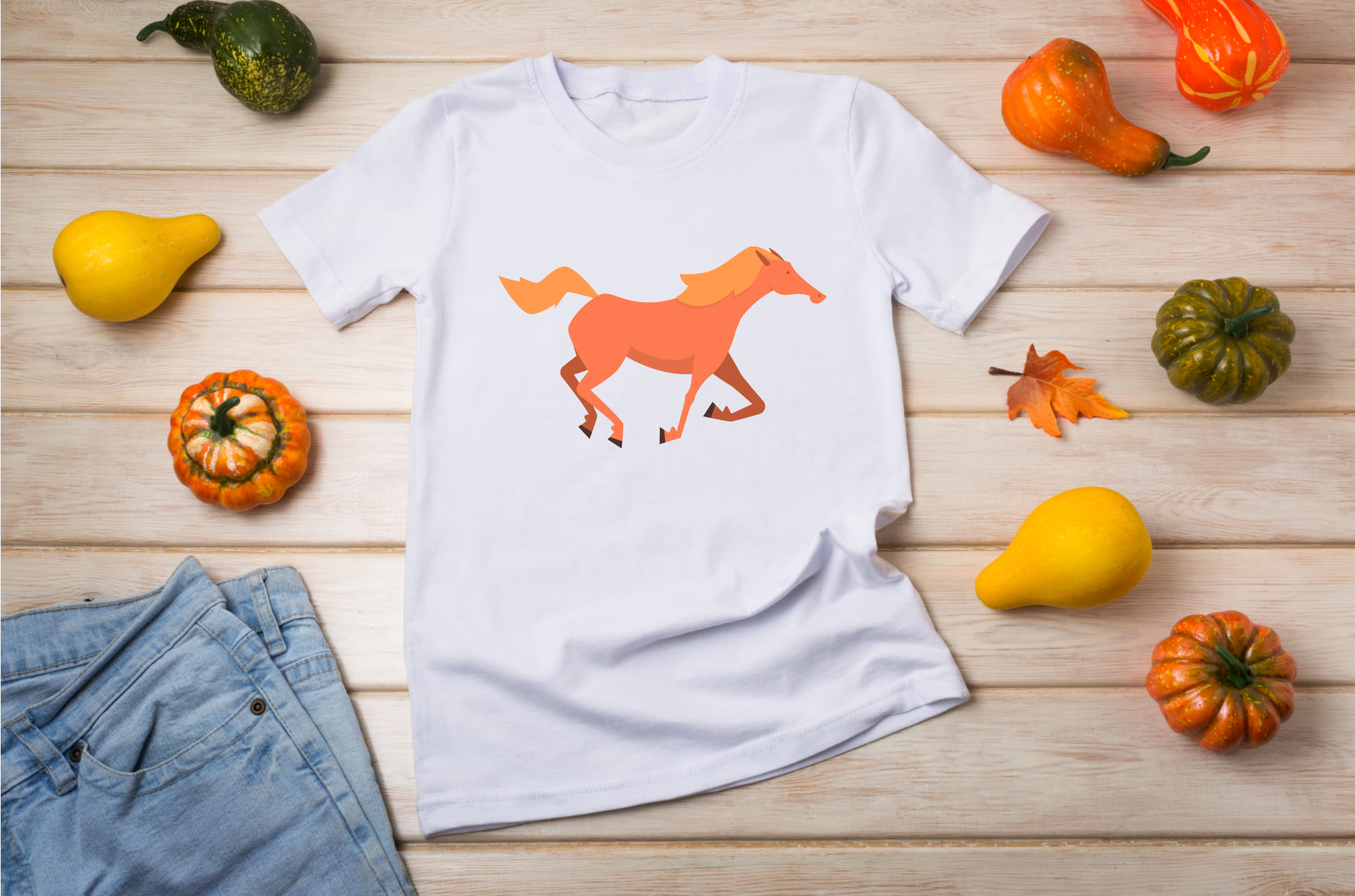 White t-shirt with a ginger mustang horse on the wooden background with pumpkins.