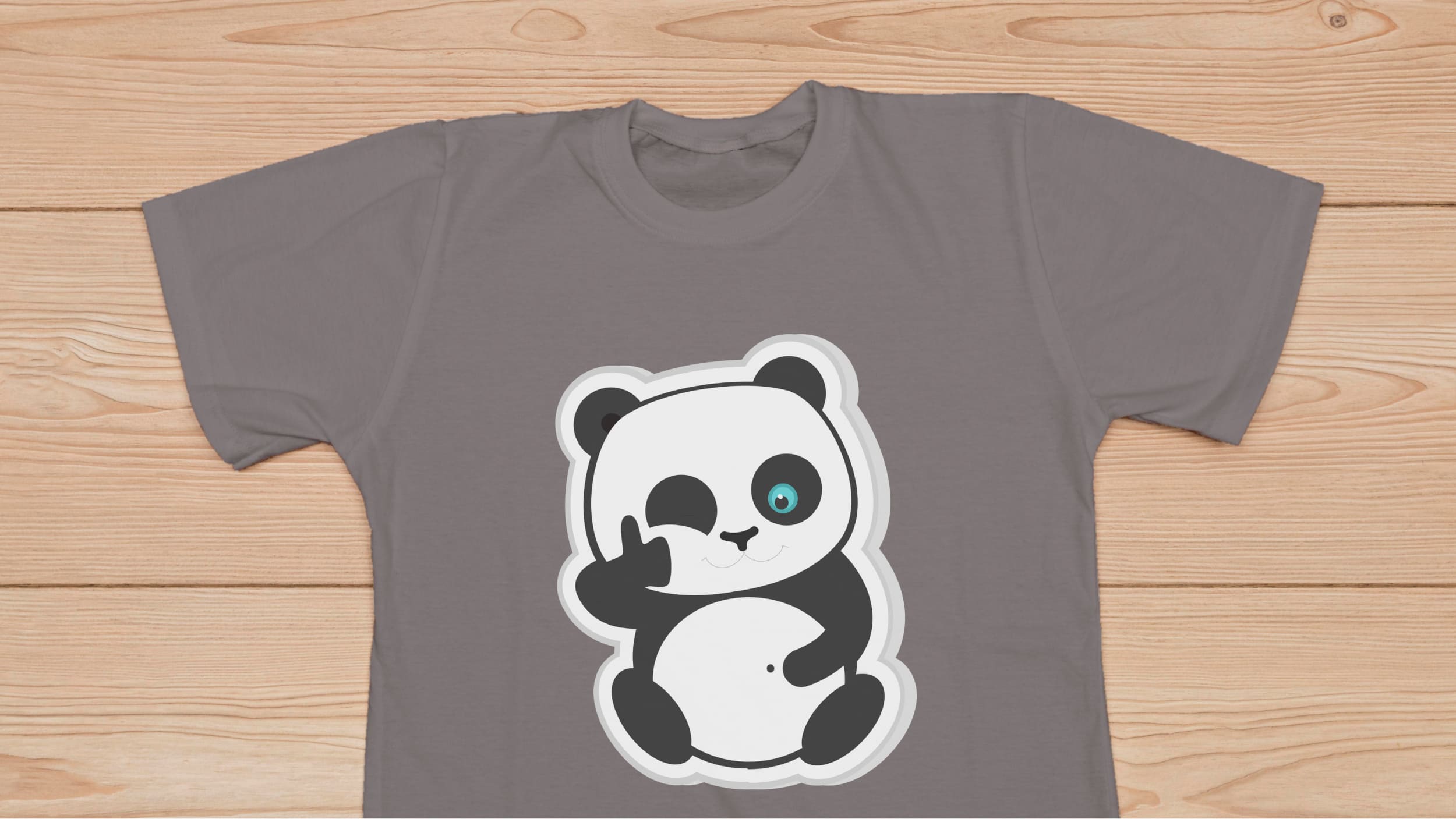Gray t-shirt with smiling panda bear on a wooden background.