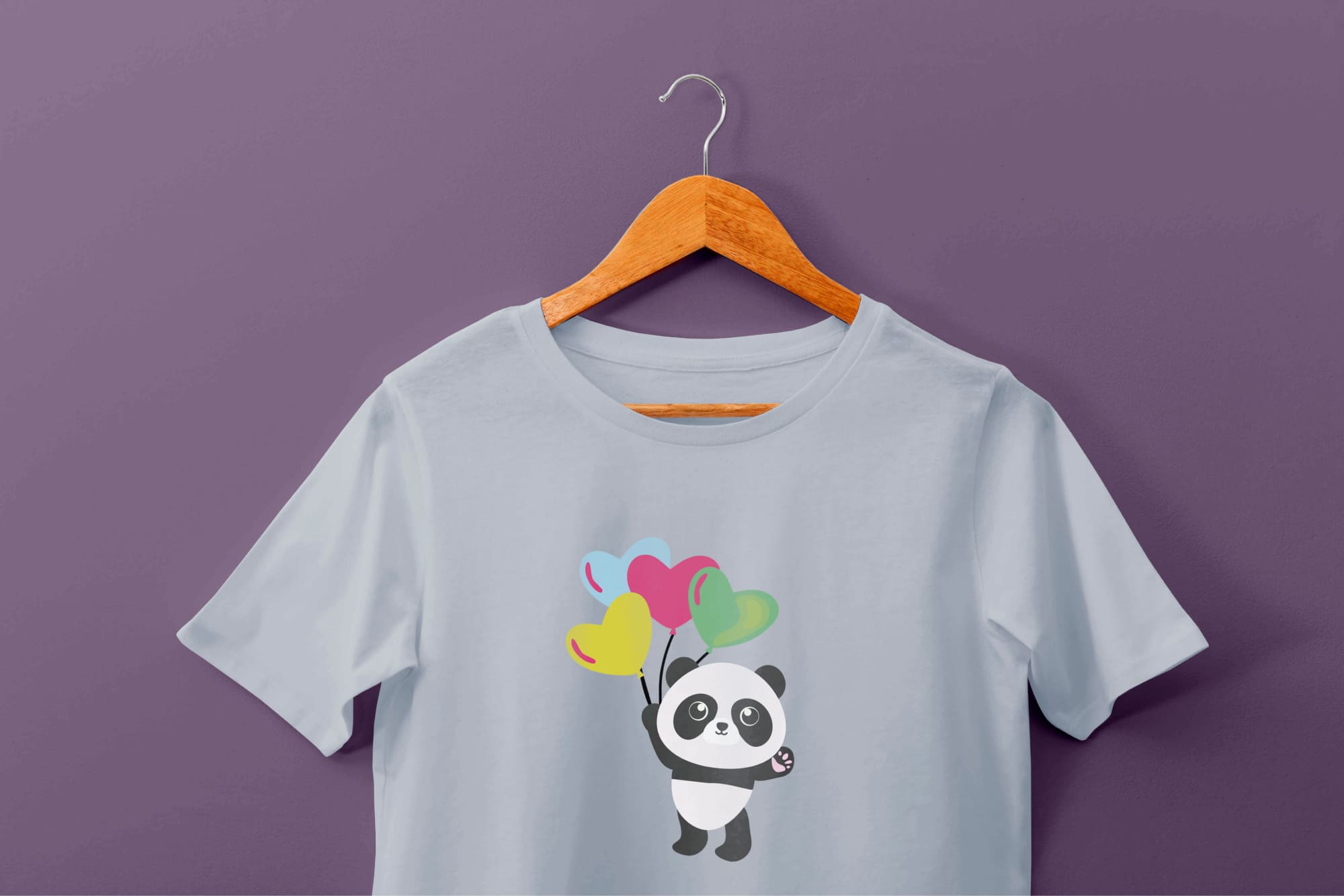 Light blue t-shirt with a panda and 4 balloon hearts on a hanger on a purple background.