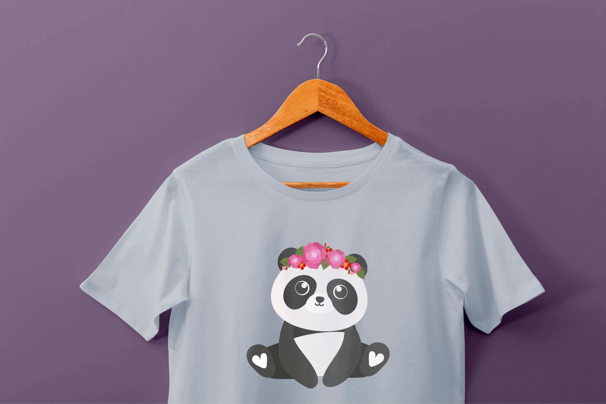 Light blue t-shirt with a panda and headband of pink flowers on a hanger on a purple background.