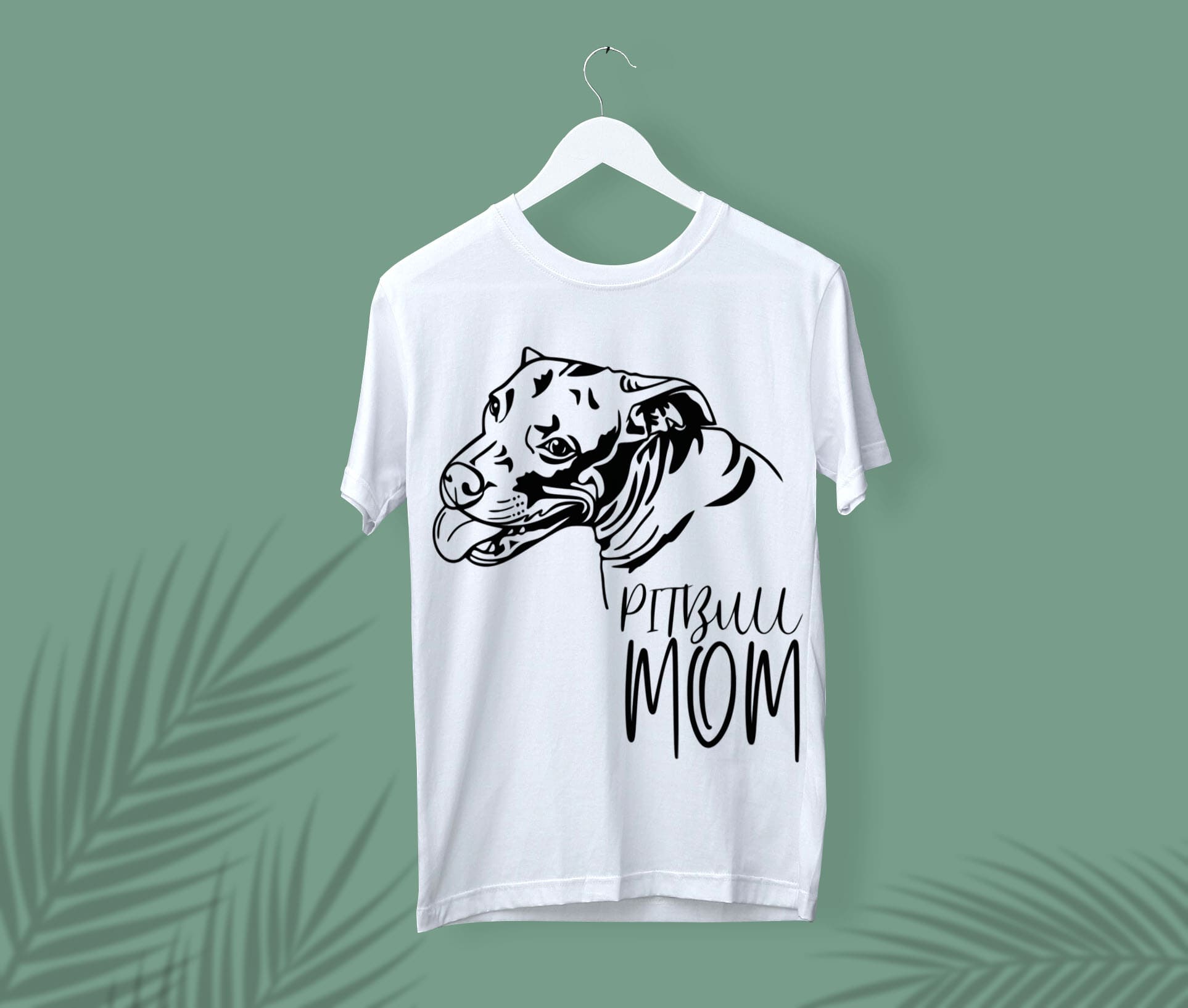 White t-shirt with a black pitbull mom face on a white hanger, on a green background.