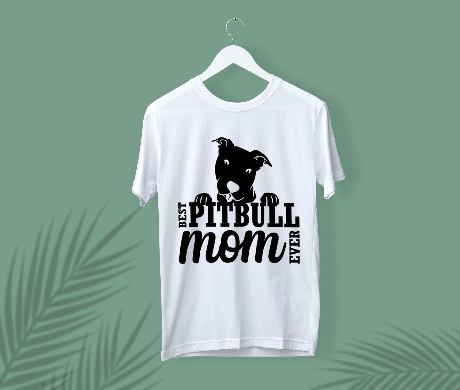 White t-shirt with a black pitbull mom face on a white hanger, on a green background.