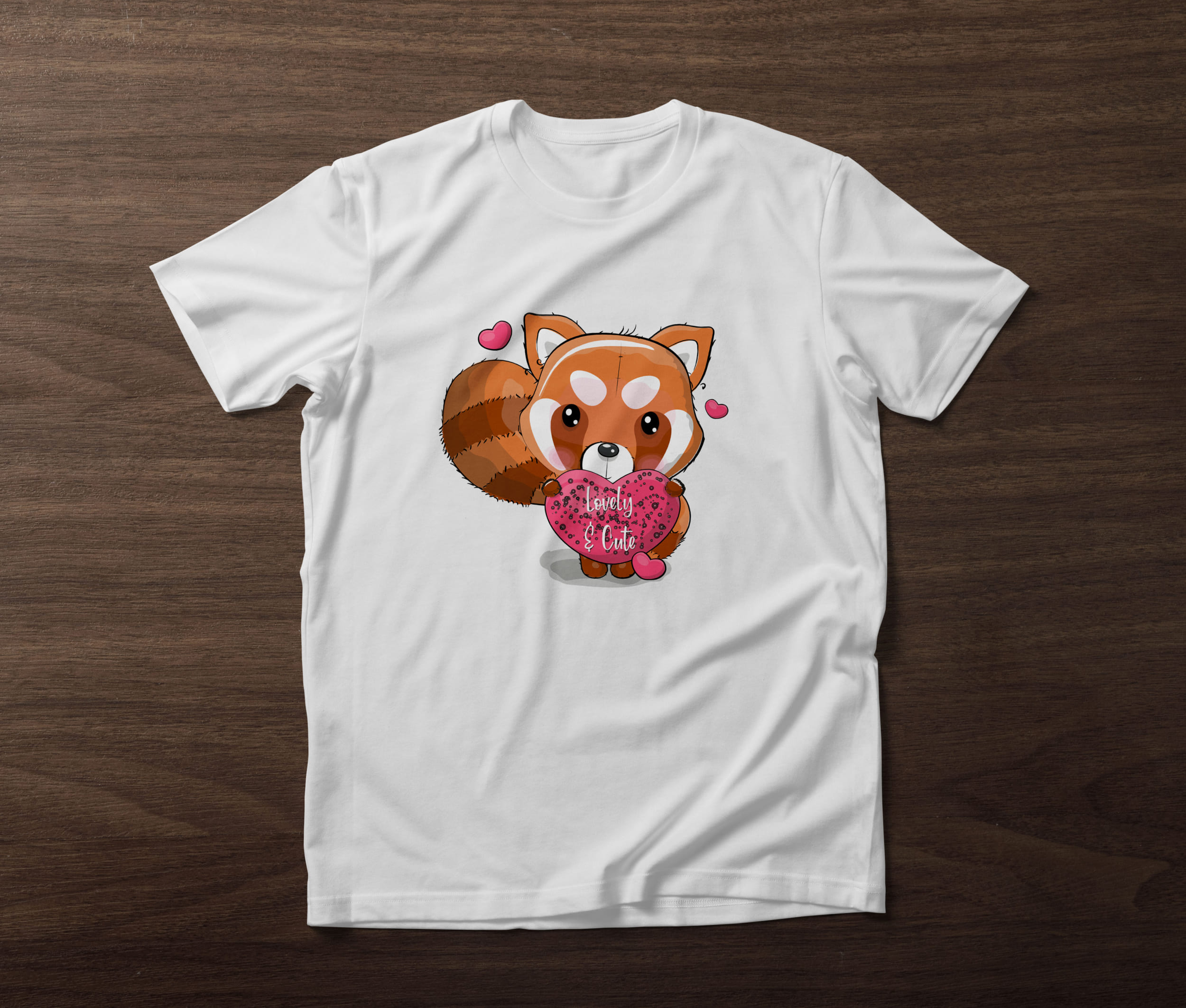 White t-shirt with a red panda and pink hearts on a wooden background.