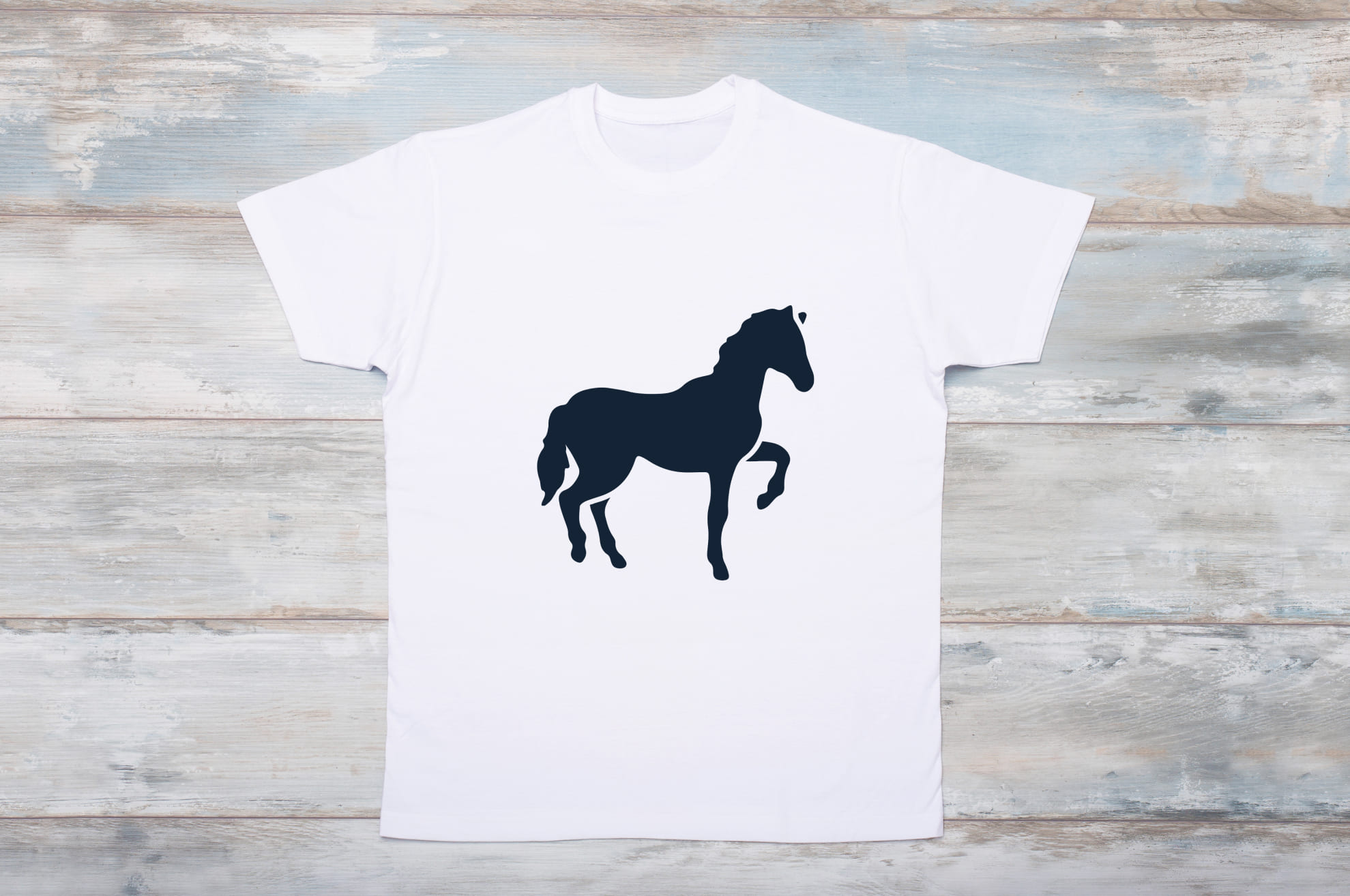 White t-shirt with a black silhouette of a horse on the wooden background.
