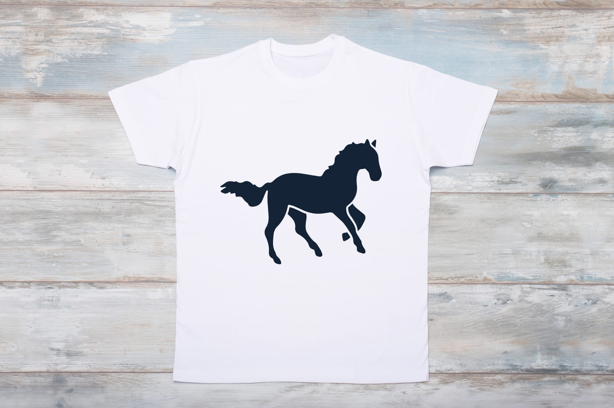 White t-shirt with a black silhouette of a running horse on the wooden background.