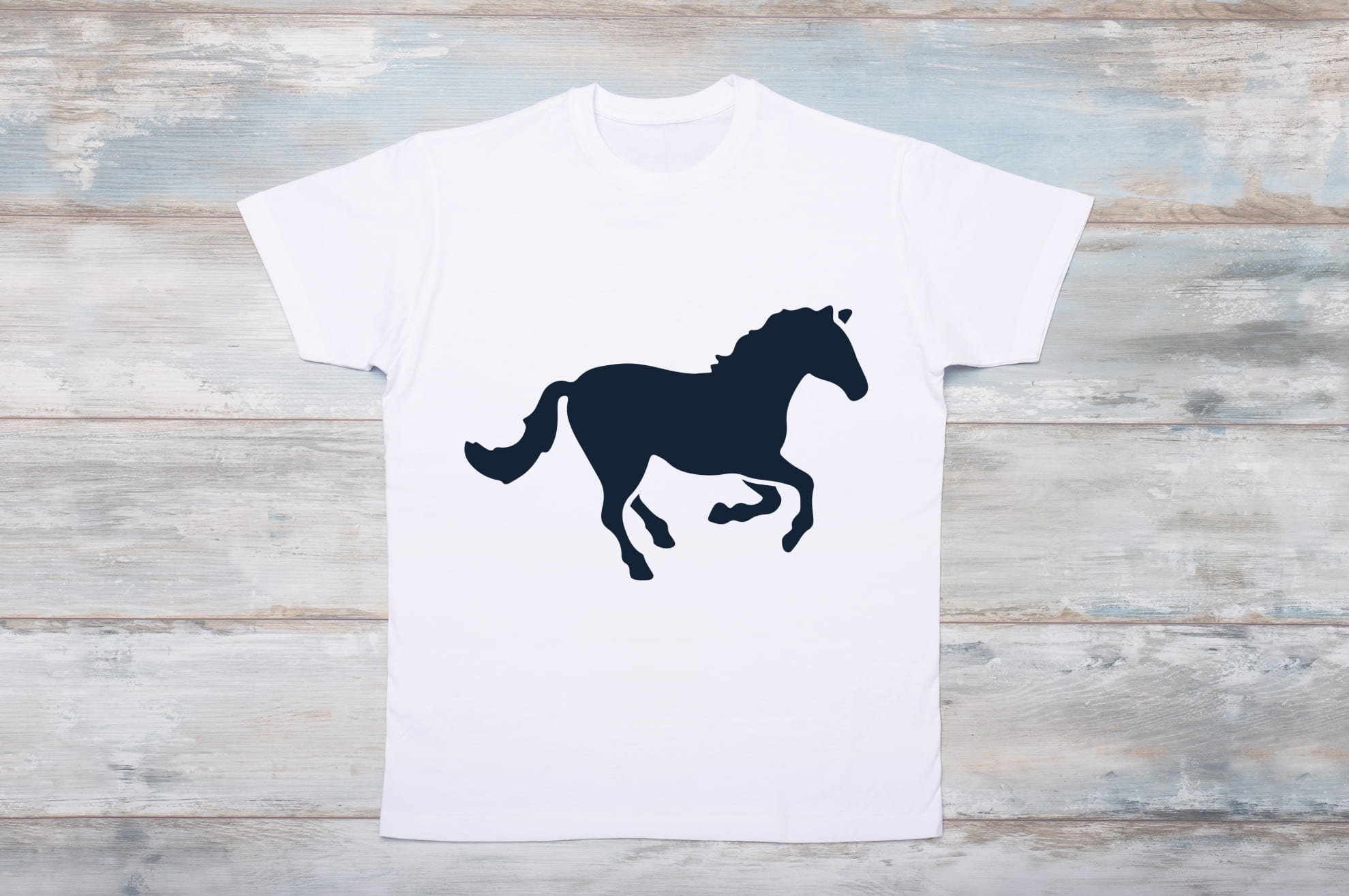 White t-shirt with a black silhouette of a running horse on the wooden background.