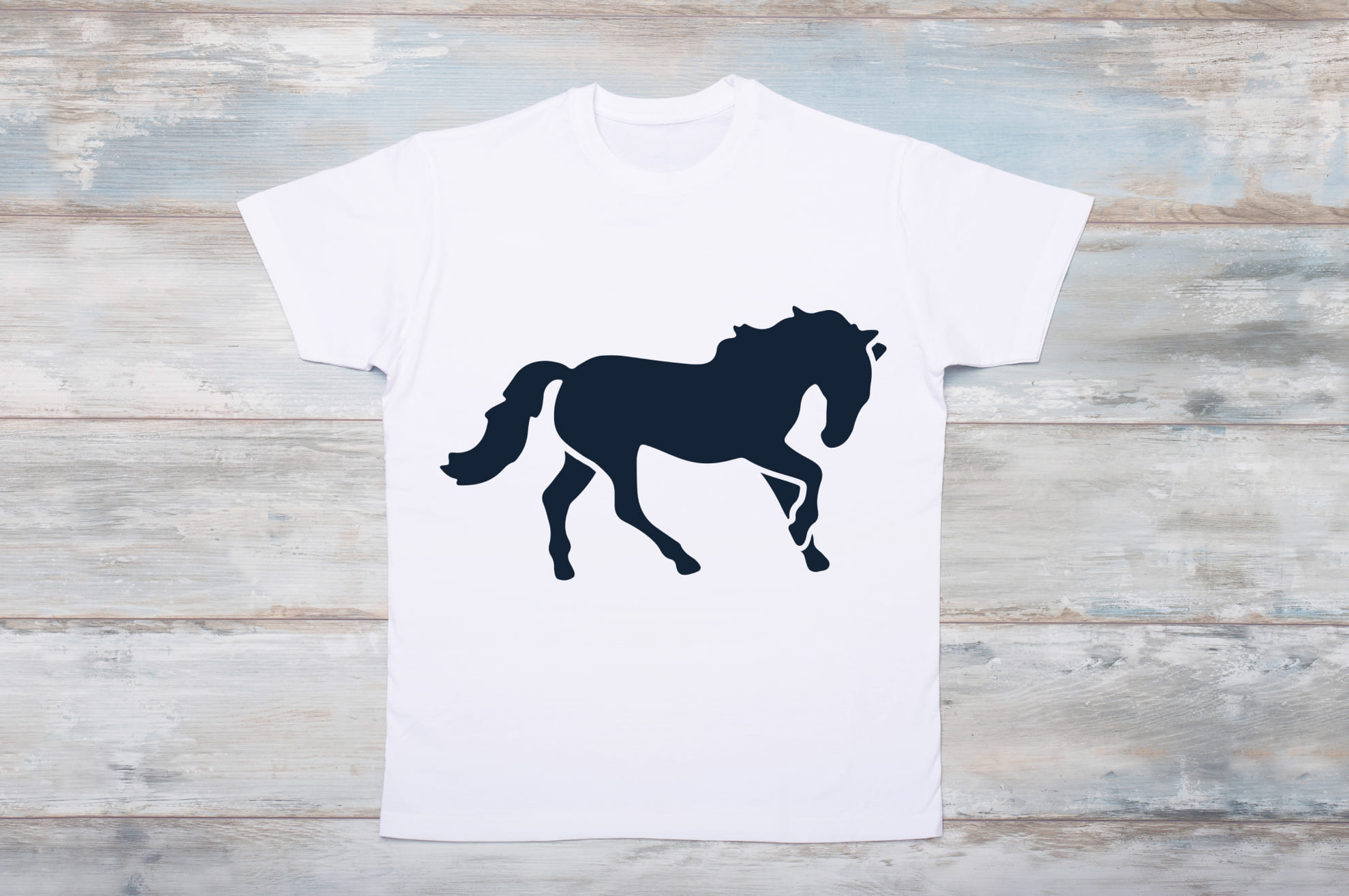 White t-shirt with a black silhouette of a cute horse on the wooden background.