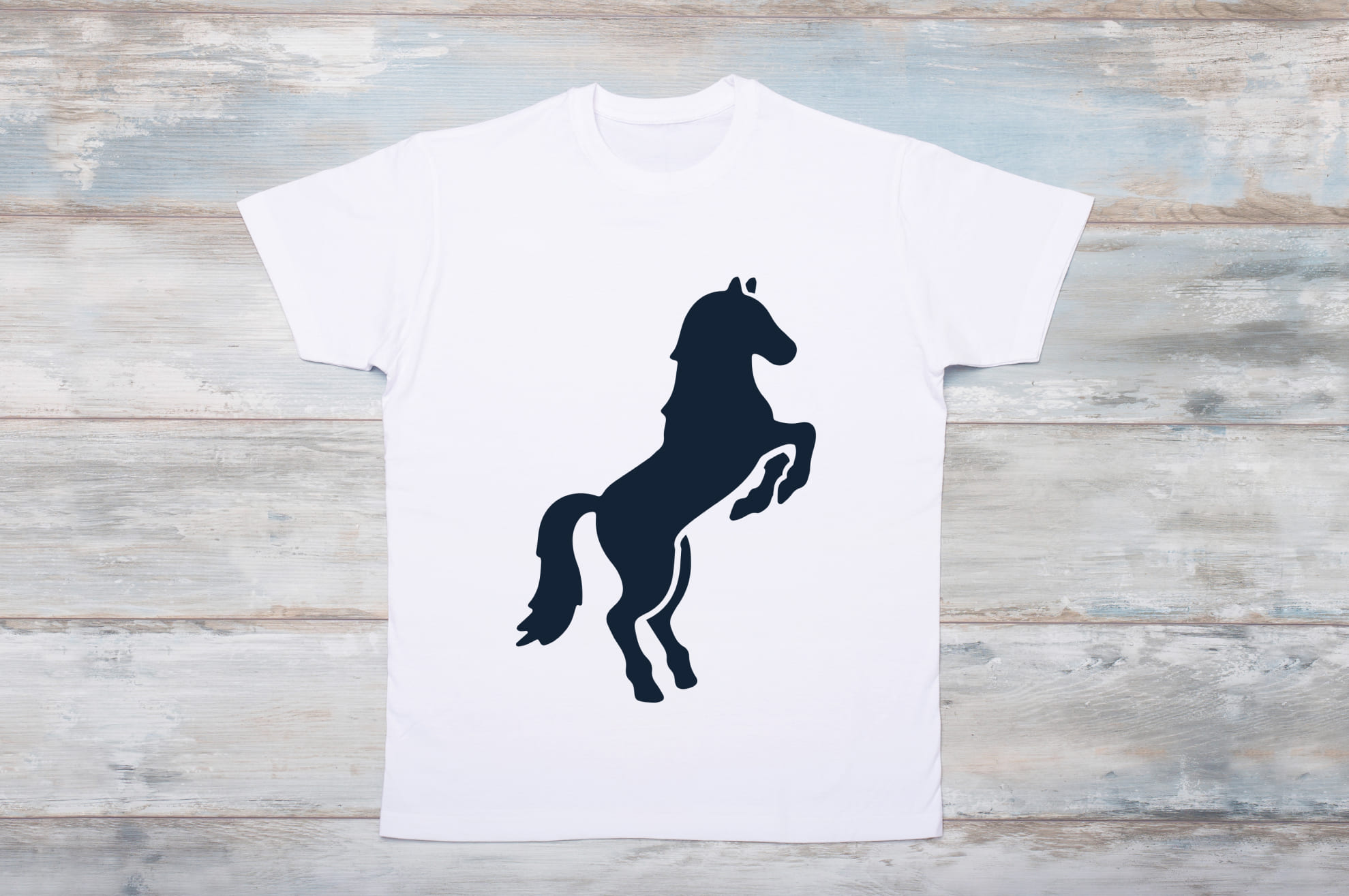 White t-shirt with a black silhouette of an energetic horse on the wooden background.