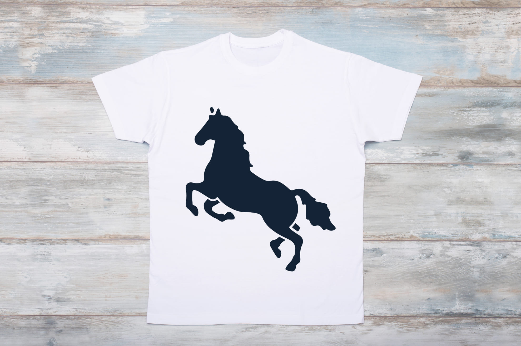 White t-shirt with a black silhouette of an energetic horse on the wooden background.