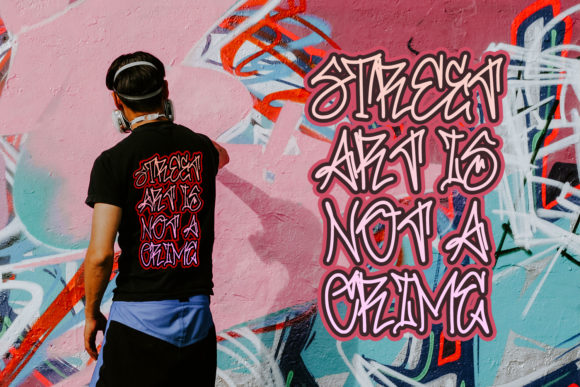 Pink and brown "Street art is not a crime" lettering in graffiti font against a cool image.