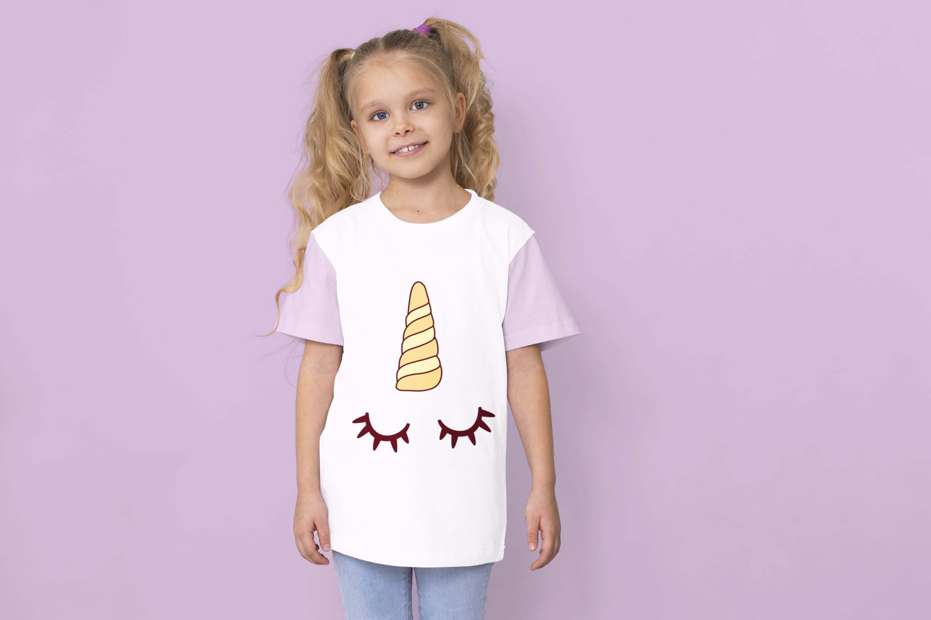 A white t-shirt with lavender sleeves and a yellow and beige unicorn horn with sleeping eyes on a girl against a lavender background.