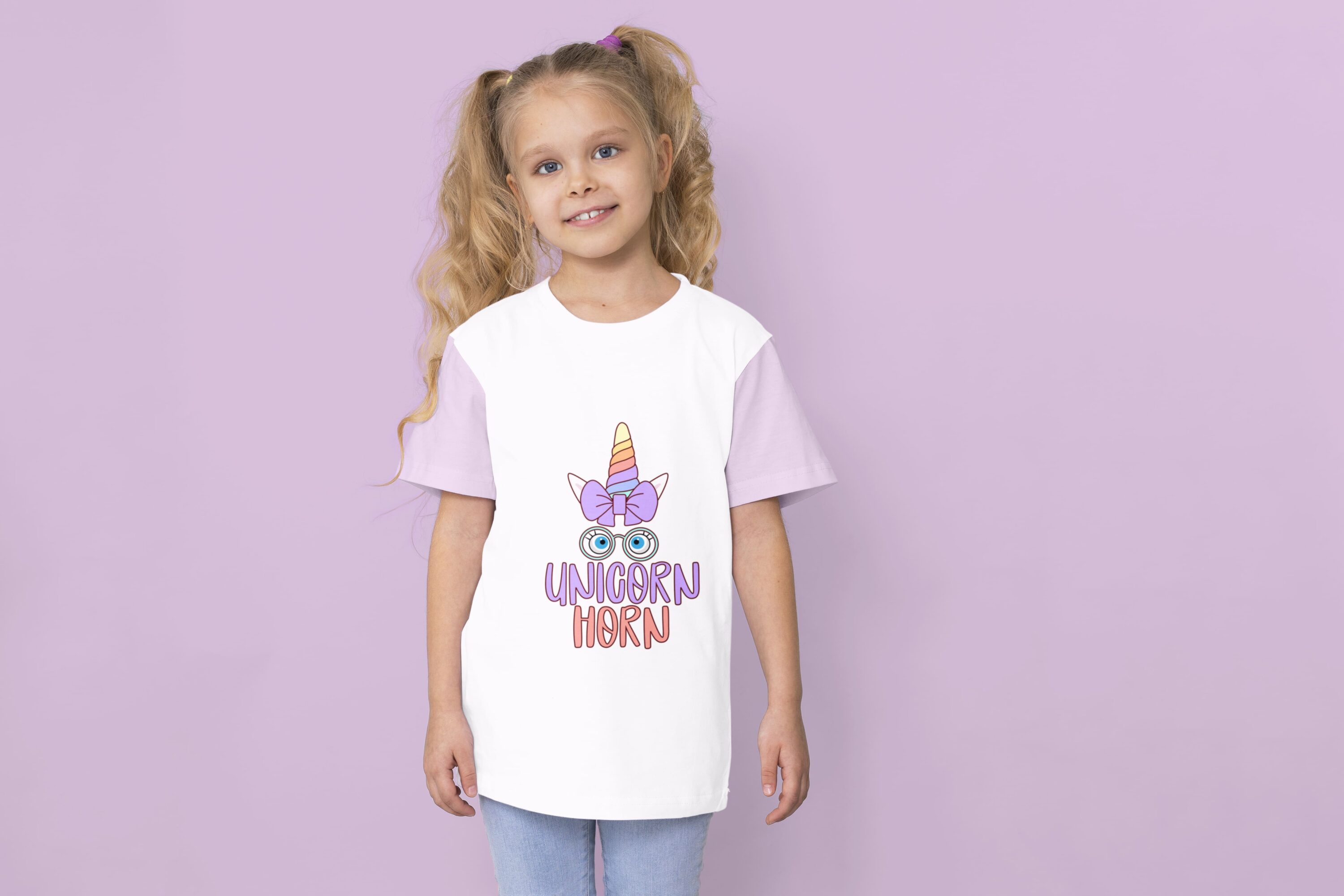 A white t-shirt with lavender sleeves and a colorful unicorn horn with eyes, glasses and lavender bow and lavender lettering "UNICORN" with pink lettering "HORN" on a girl against a lavender background.