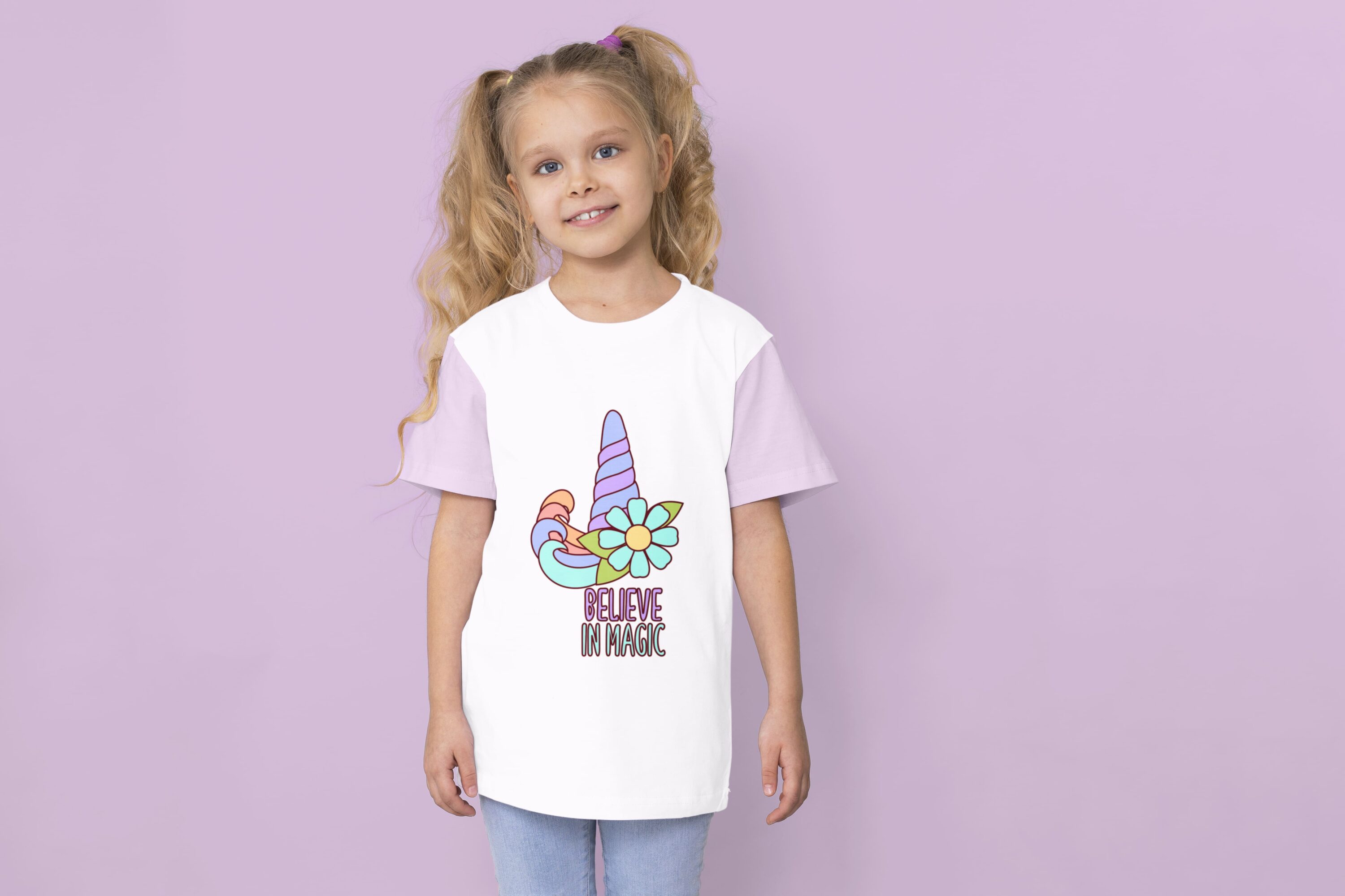 A white t-shirt with lavender sleeves and a blue and purple unicorn horn with a flower and purple lettering "Believe" with blue lettering "in magic" on a girl against a lavender background.