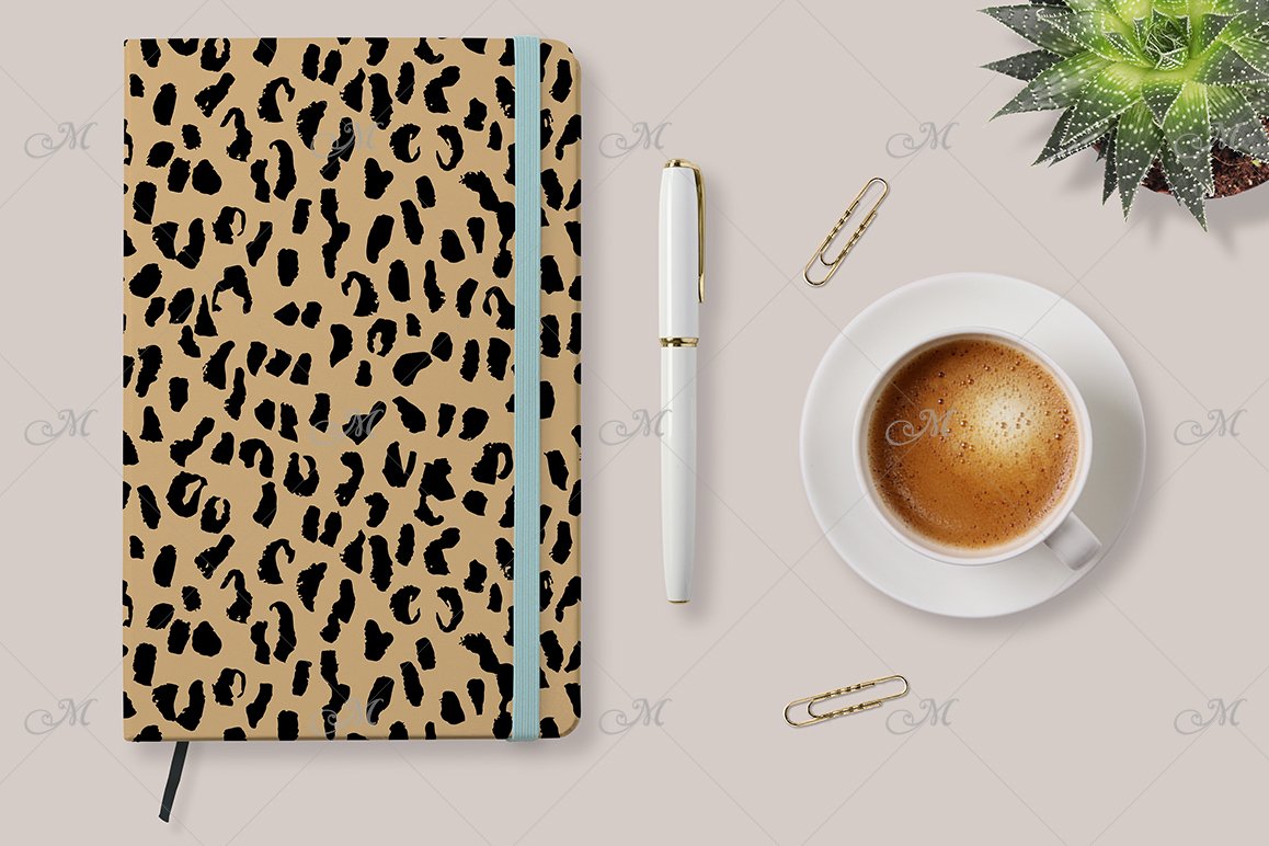 Leopard print notebook mockup with a light blue rubber band bookmark, a white pen and a white cup of coffee on a white background.