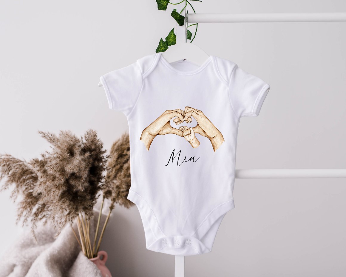 Baby bodysuit with illustration of heart mother and kid hand and black lettering "Mia".