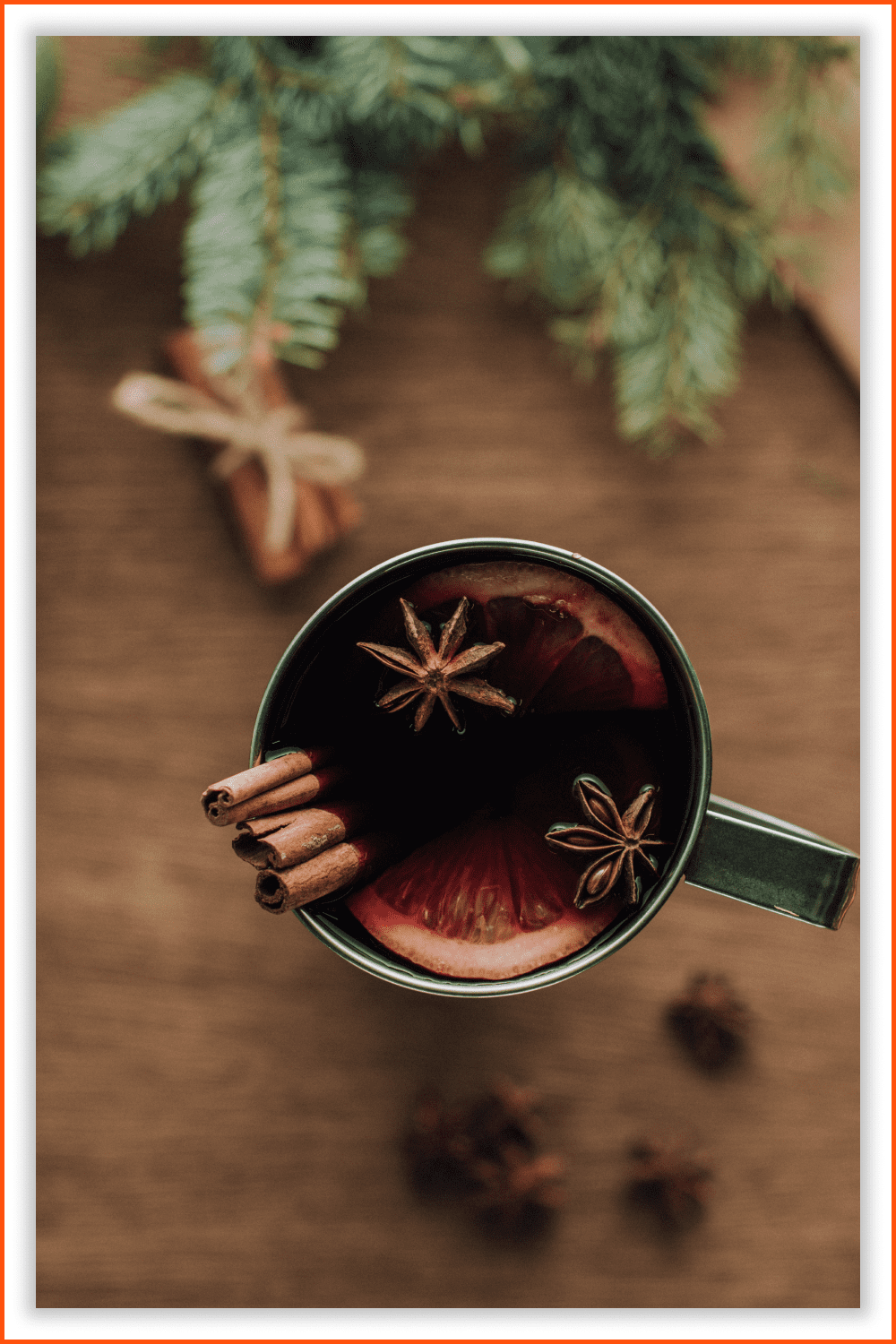 Photo of a Cup of homemade mulled wine with cinnamon sticks on a wooden tabletop.