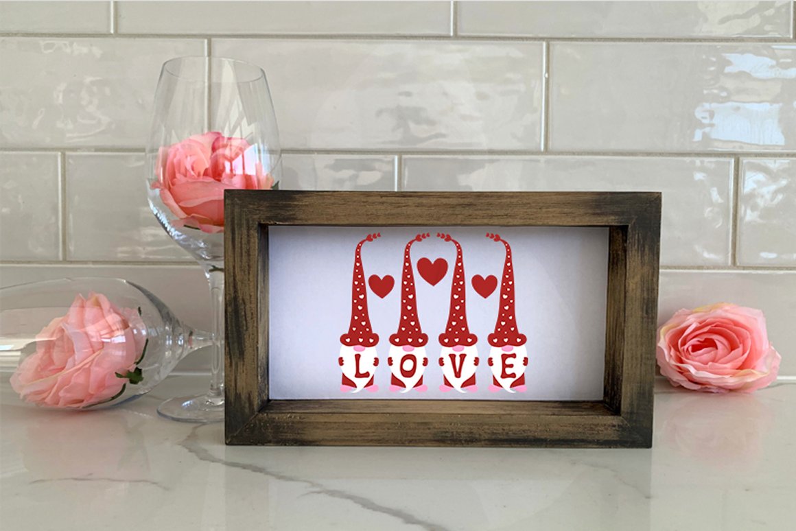 Painting with red lettering "LOVE" and illustrations of a Valentine's gnome in brown frame.