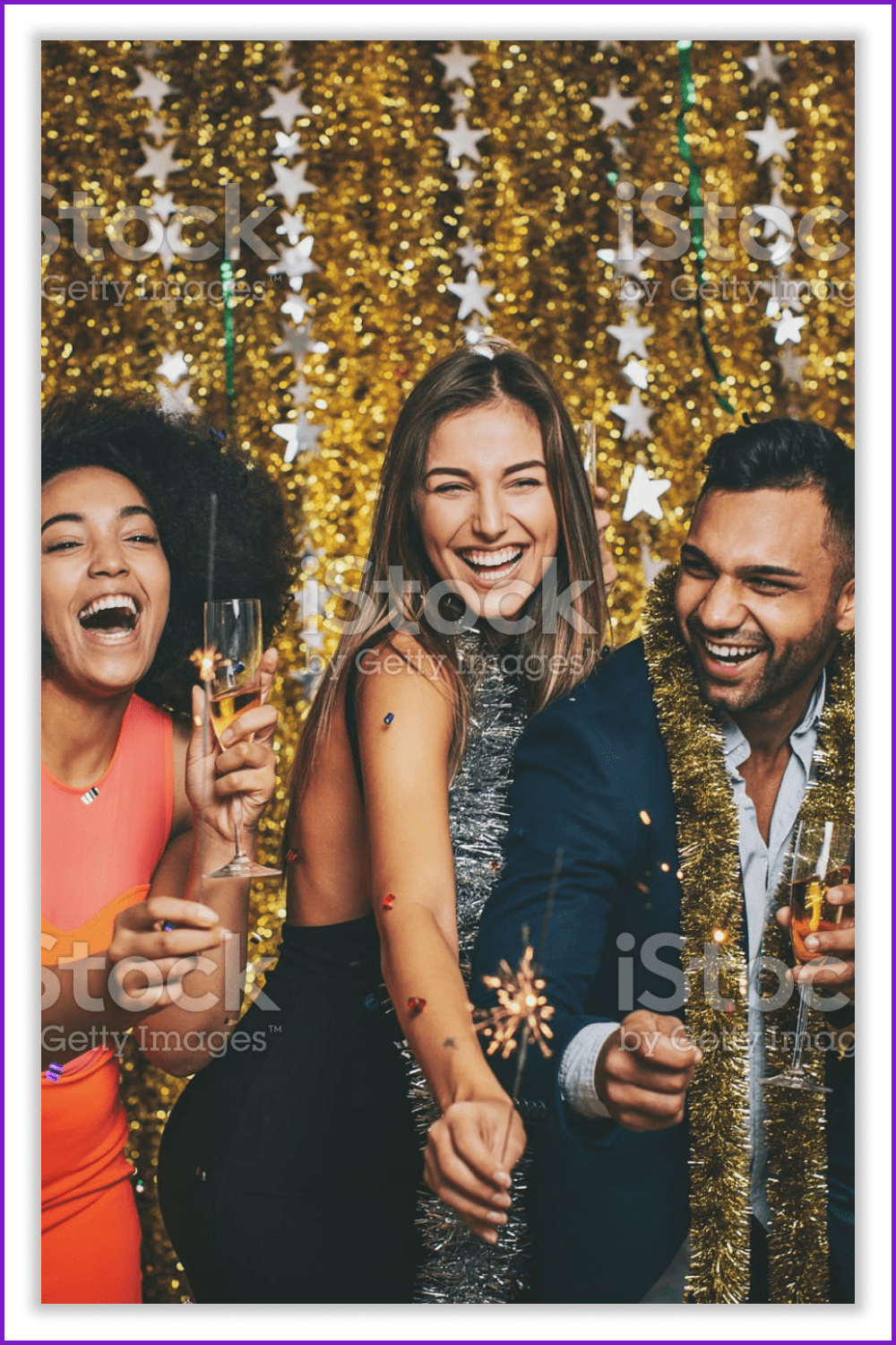 Two women and a man in New Year's decorations smile and laugh.