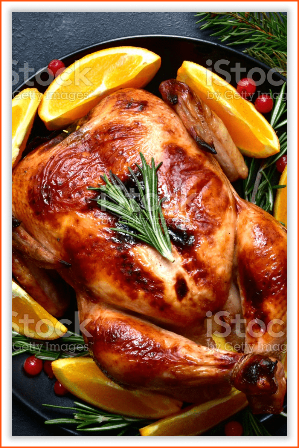 Photo of a Roasted Christmas chicken with oranges, rosemary, and cranberries.