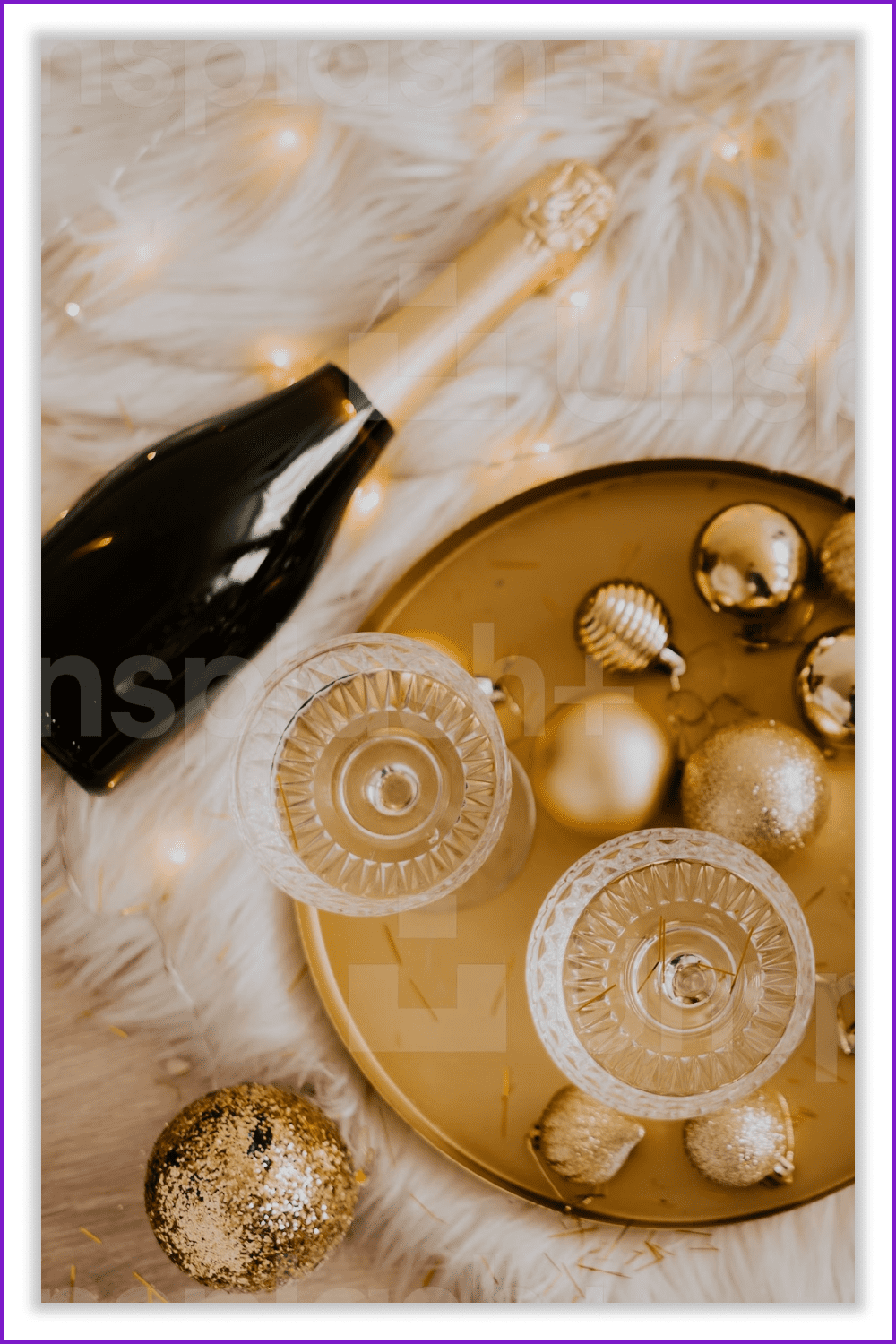 Top view of champagne bottle and tray with glasses and christmas decorations.