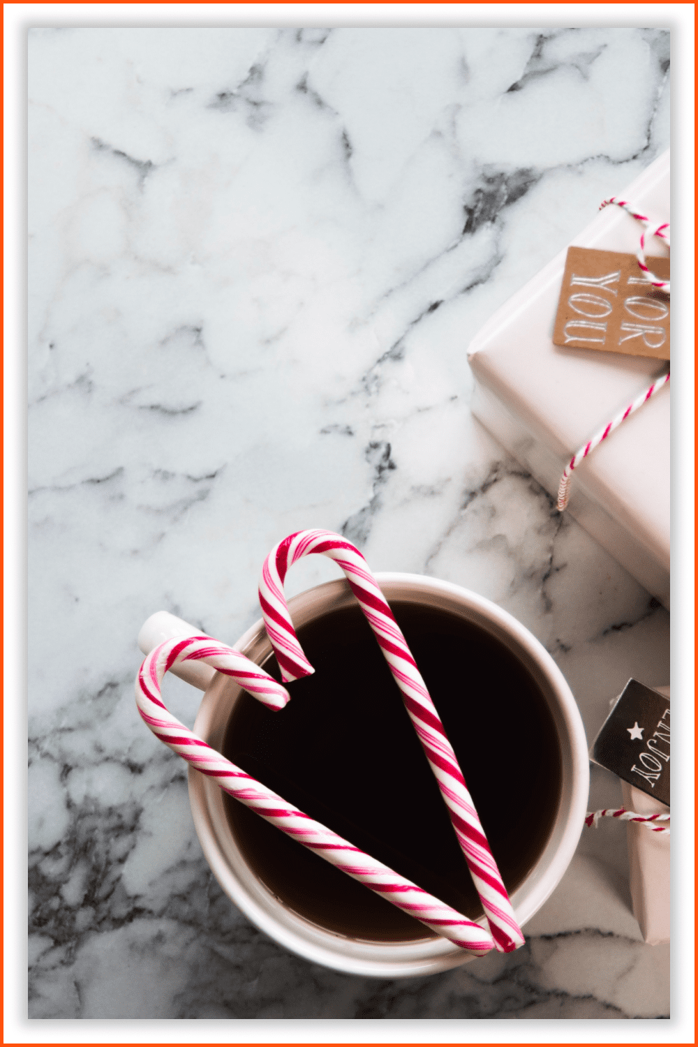 Photo of a two gifts and coffee cup with candy canes in a heart shape.