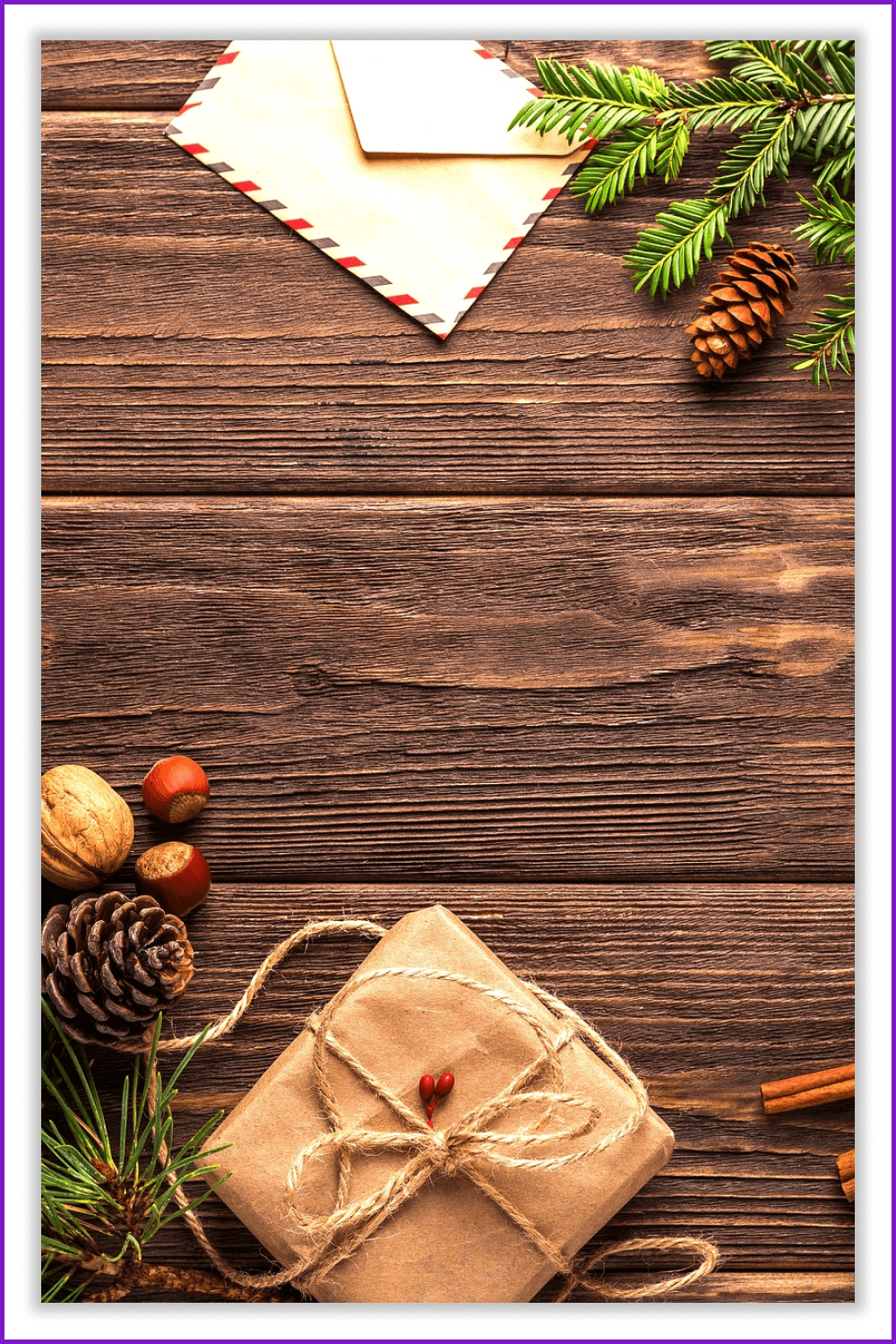 Photo of a wooden table with a gift, an envelope and fir branches on it.