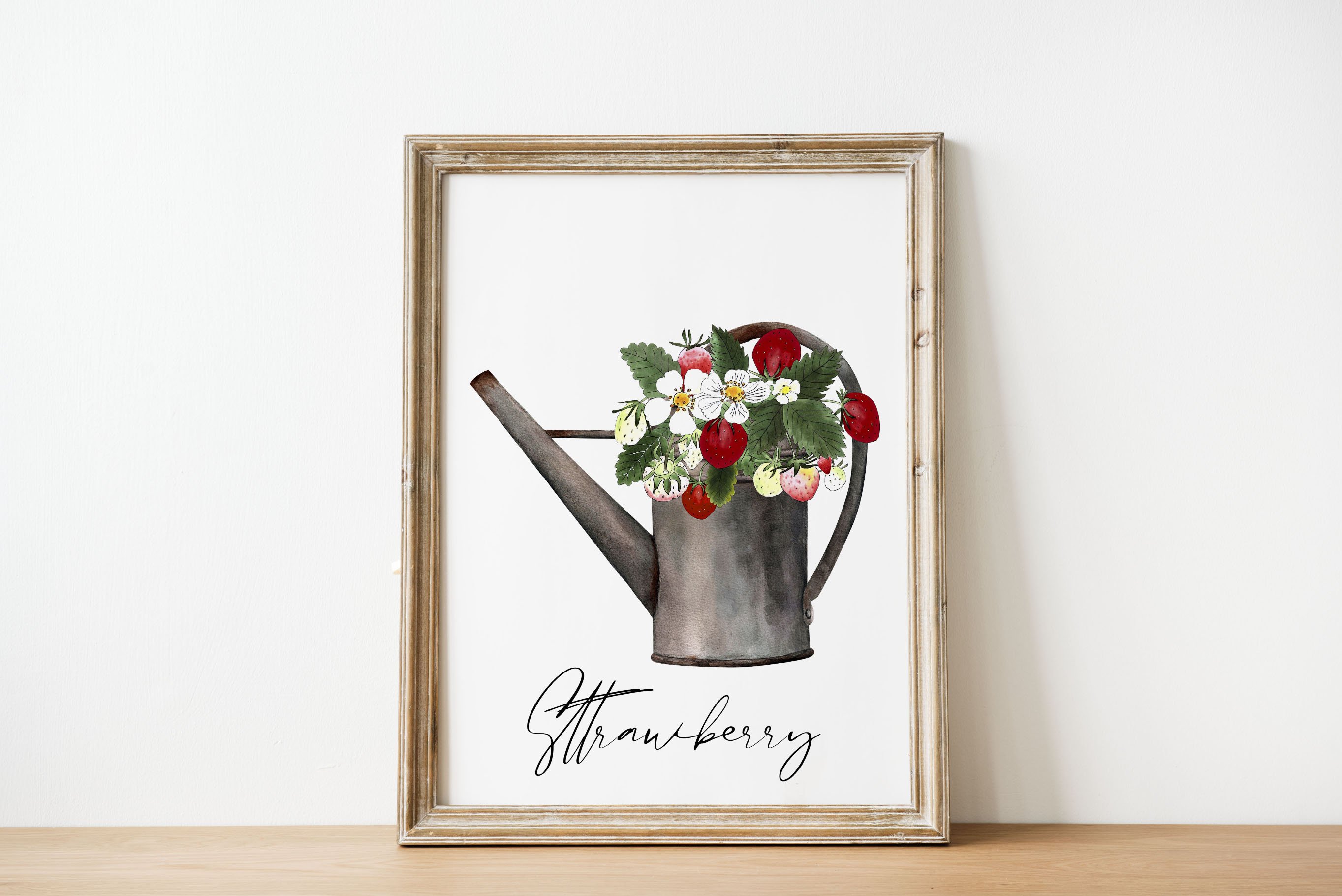 White painting in golden frame with black lettering Strawberry" and illustration of a strawberry in watering can.