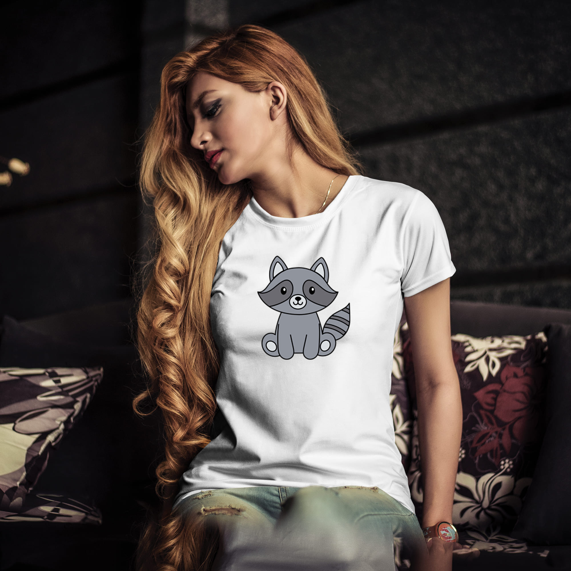 Woman sitting on a couch wearing a t - shirt with a raccoon.