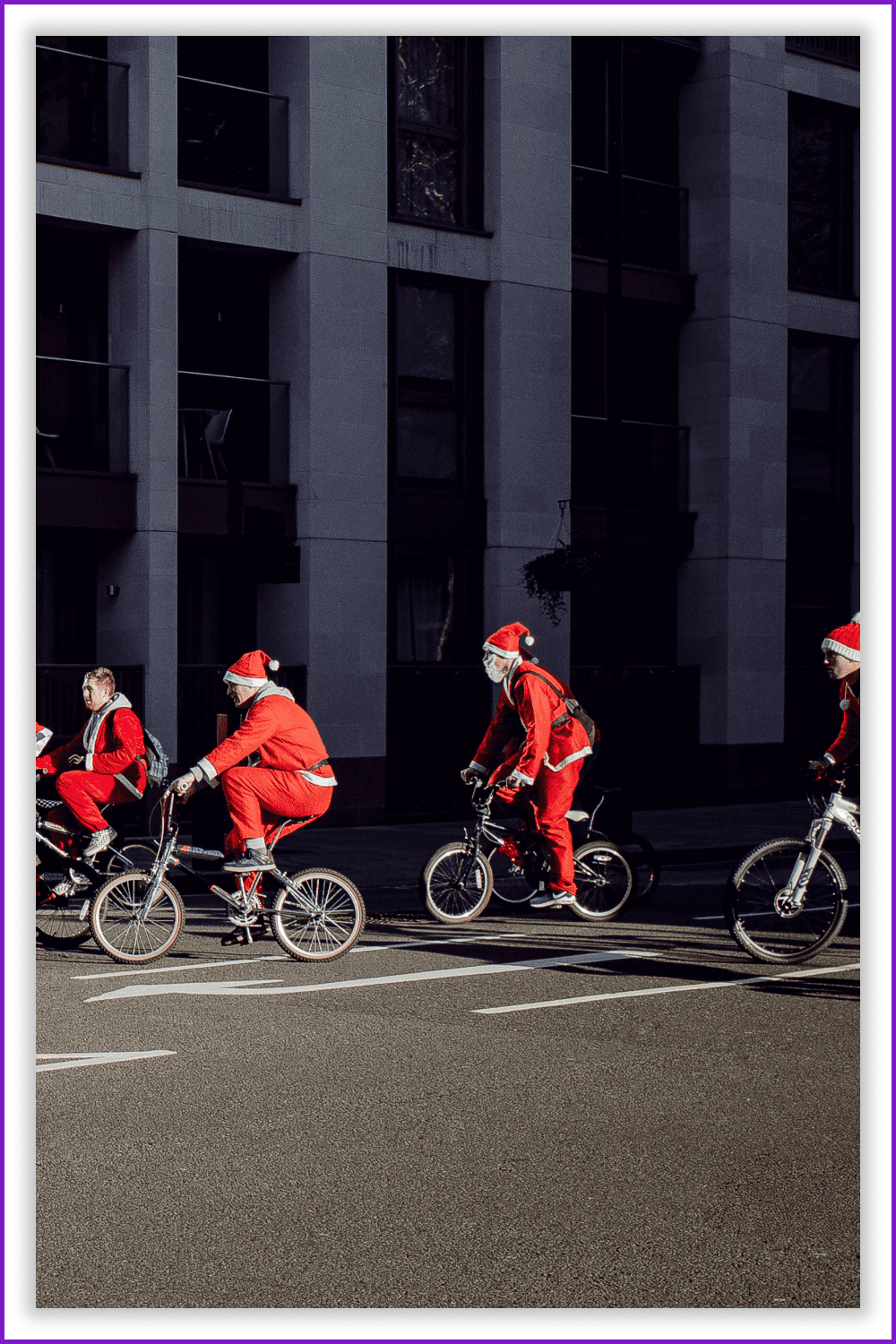 Photo of Santa Clauses on bicycles on the road in the city.