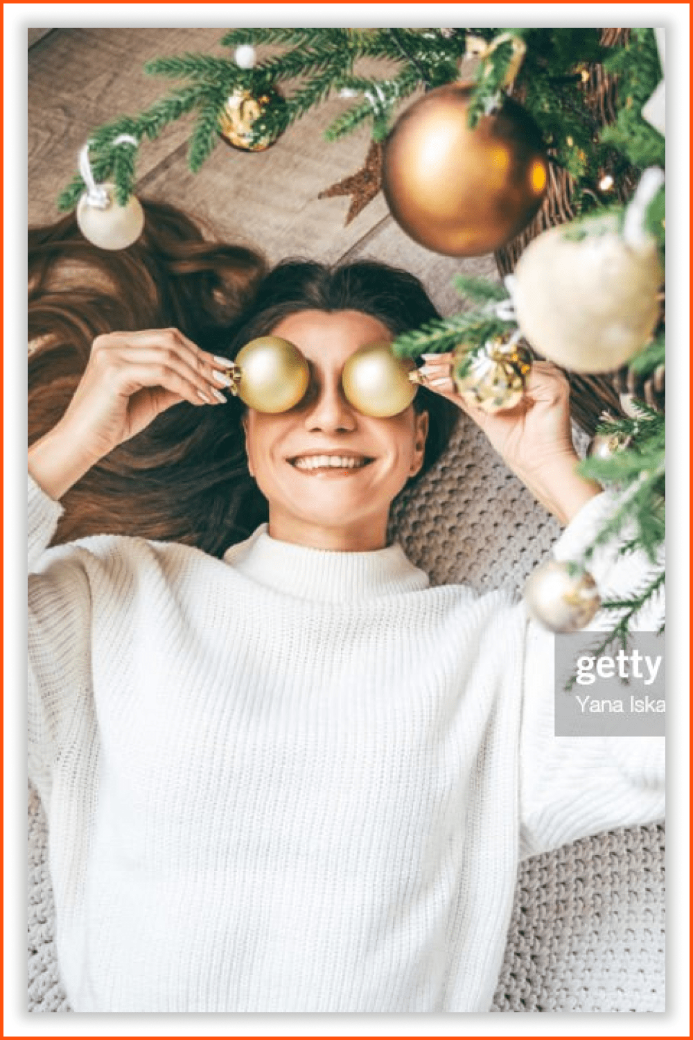 A smiling woman in a white sweater with Christmas toys above her eyes.
