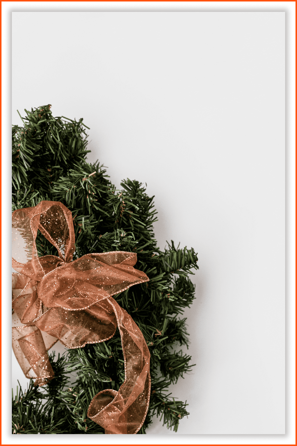 A photo of a Christmas wreath with bow made from organza fabric and a metal vintage bauble.