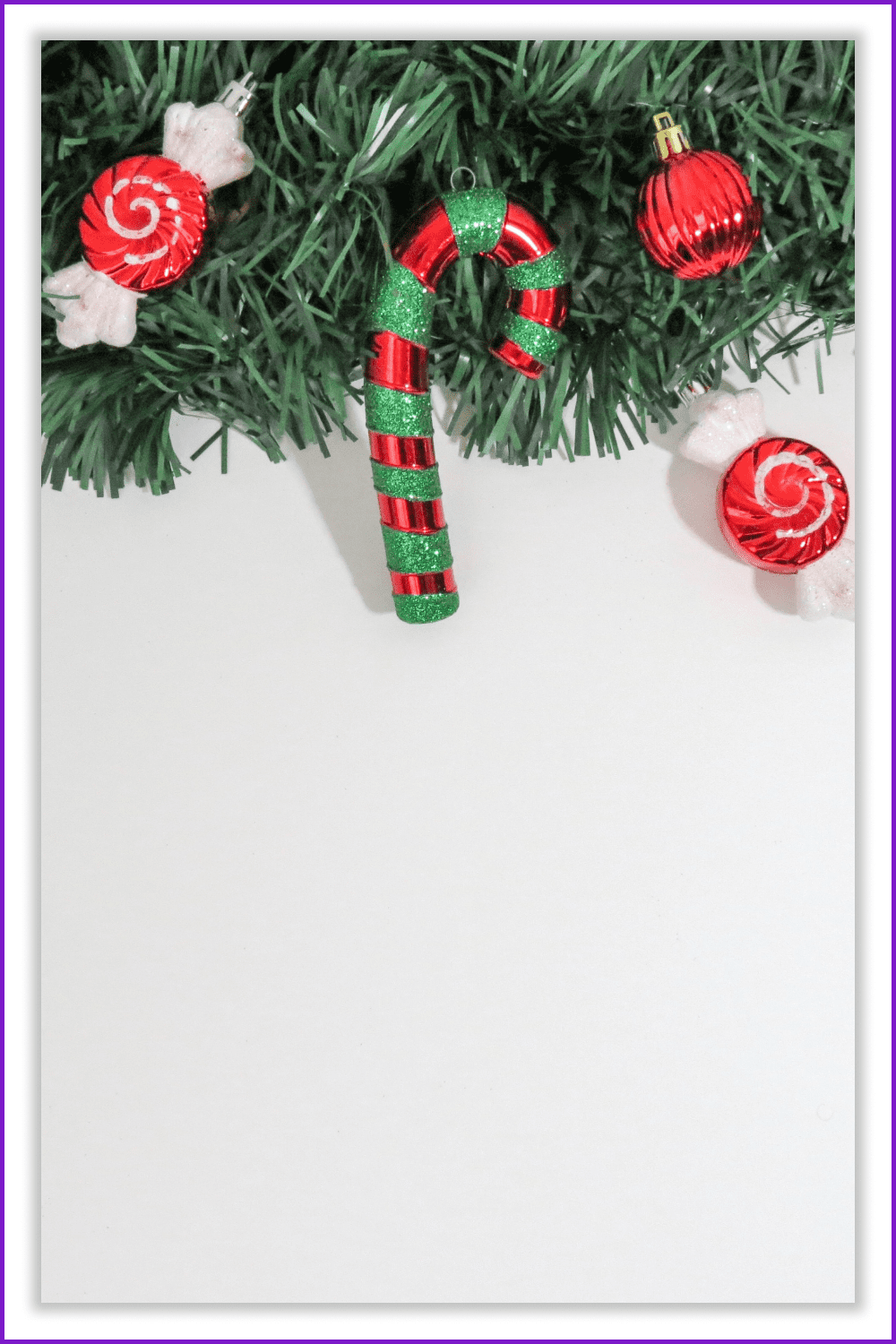 Photo of a Christmas tree branch with Christmas decorations on a white background.