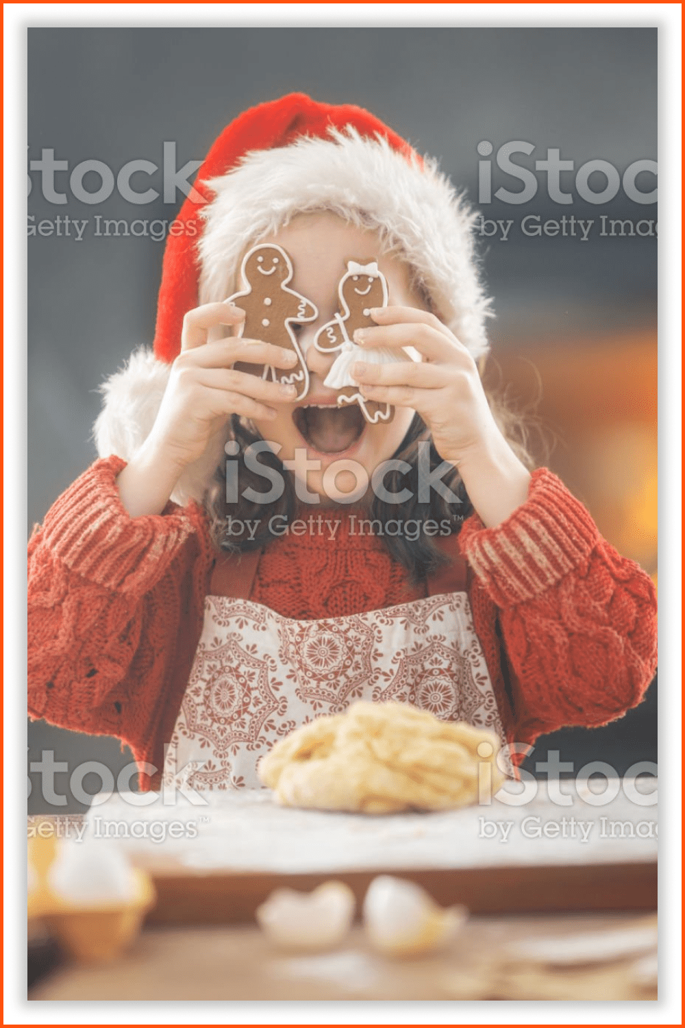 A little girl in a Santa hat with freshly baked gingerbreads.