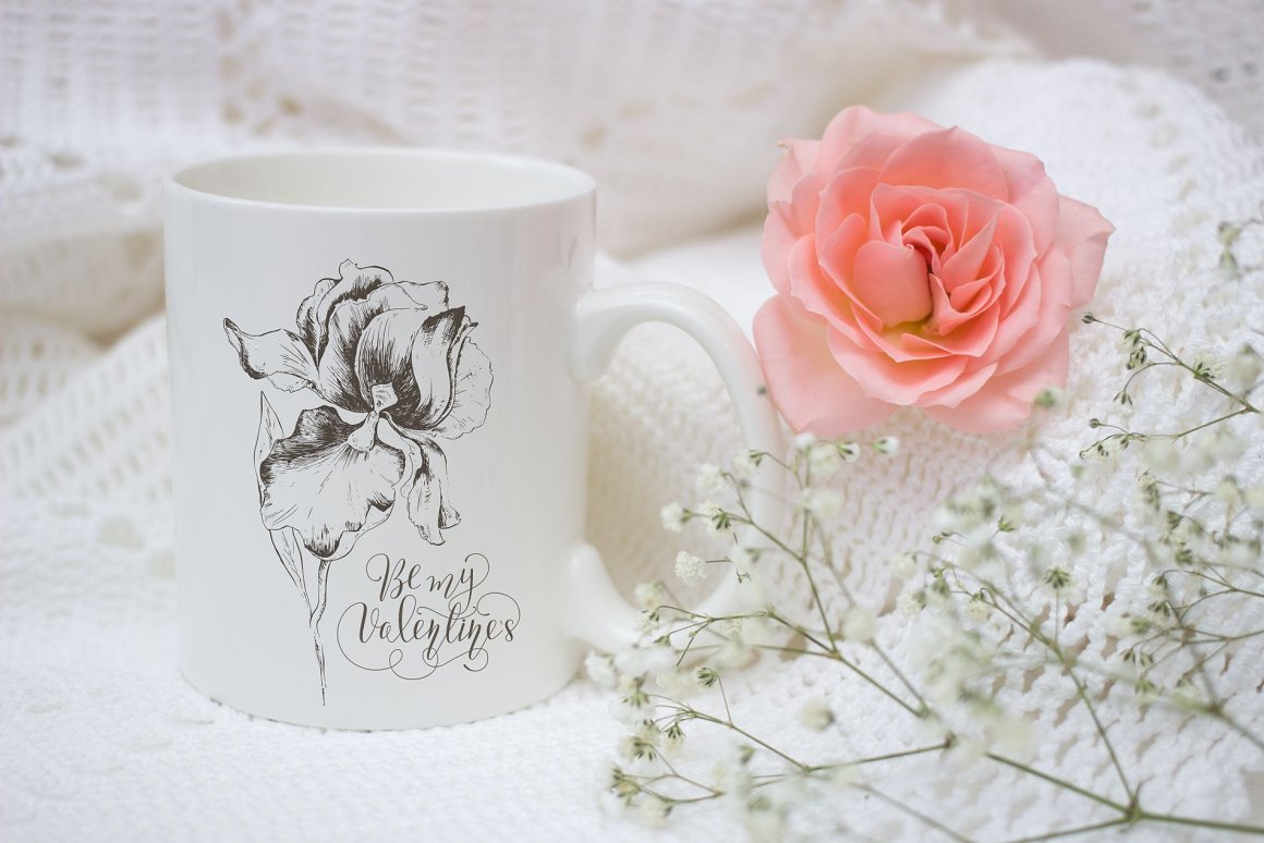 White cup with black illustration of a flower and black calligraphic phrase.