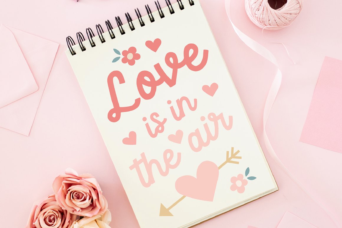 White spiral notebook with pink lettering "Love is in the air" on a pink background.