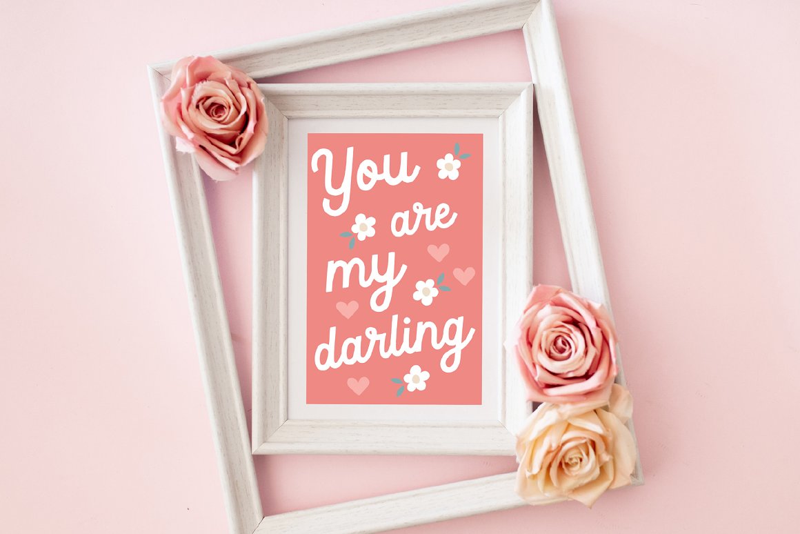 Art board with white lettering "You are my darling" on a pink background with hearts and flowers in white frame.