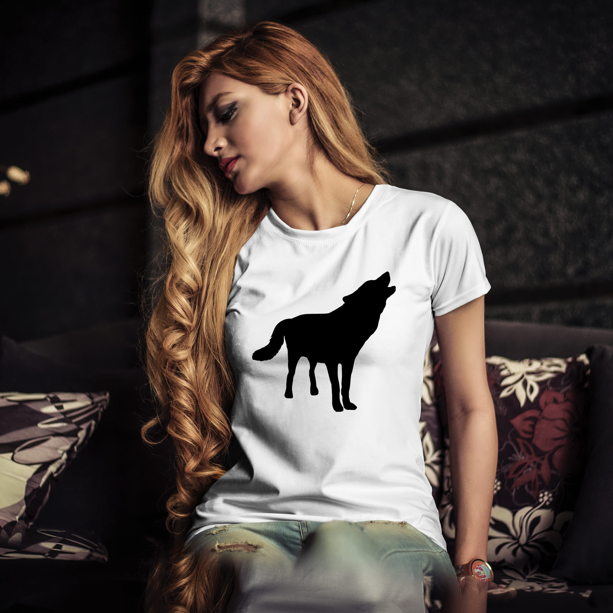 Woman sitting on a couch wearing a t - shirt with a wolf on it.
