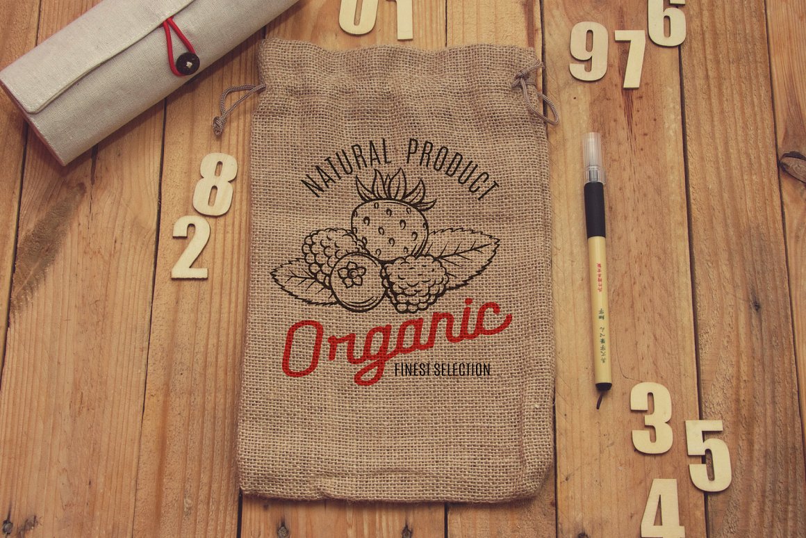 A beige bag with black vintage illustration of berries and red lettering "Organic" on the wooden background.