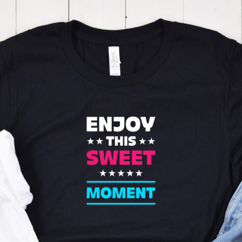 Image of a black t-shirt with an exquisite "enjoy this sweet moment" lettering in red and turquoise and white colors.