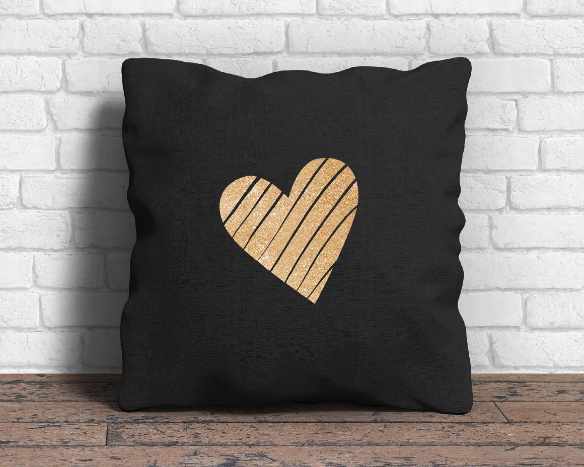 Black pillow with a golden glitter heart on the wooden background.
