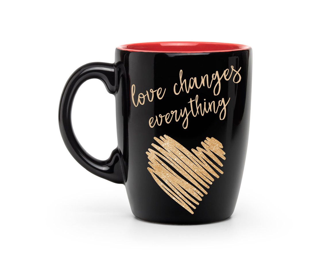 Black cup with a golden glitter heart and golden lettering "Love changes everything" on a white background.