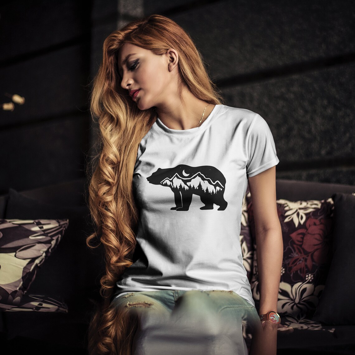 Woman sitting on a couch wearing a t - shirt with a bear on it.