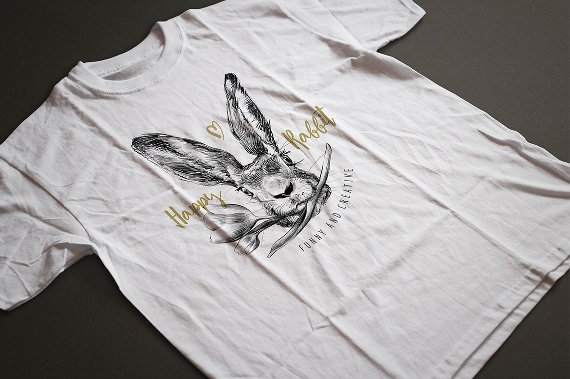 White t-shirt with golden lettering "Spring Rabbit" and black-white illustration of easter rabbit with tulip on a gray background.