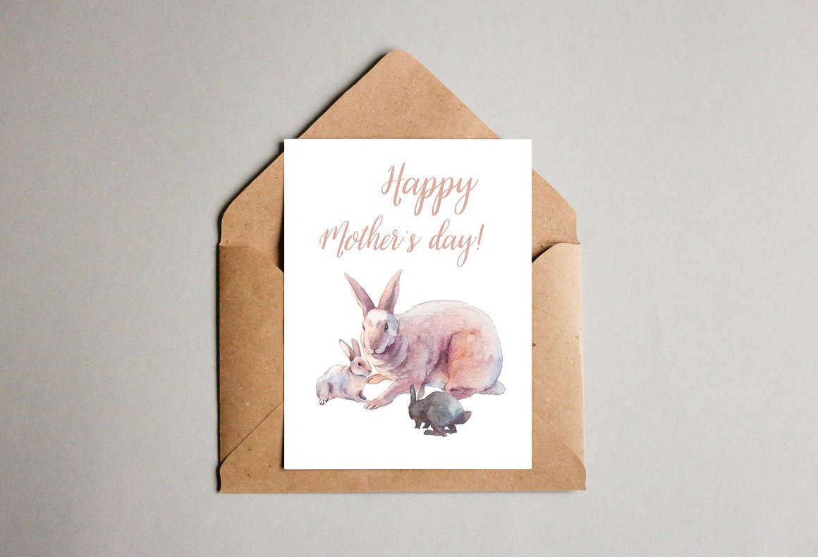 Craft envelope and a white greeting card with pink lettering "Happy mother's day!" and illustration of easter rabbits on a gray background.