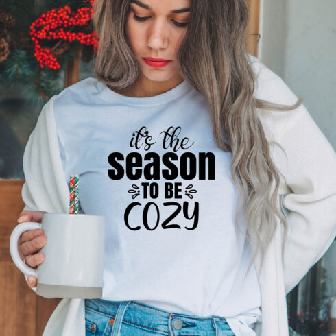 The image of a girl in a white t-shirt with an enchanting inscription "Its The Season To Be Cozy".