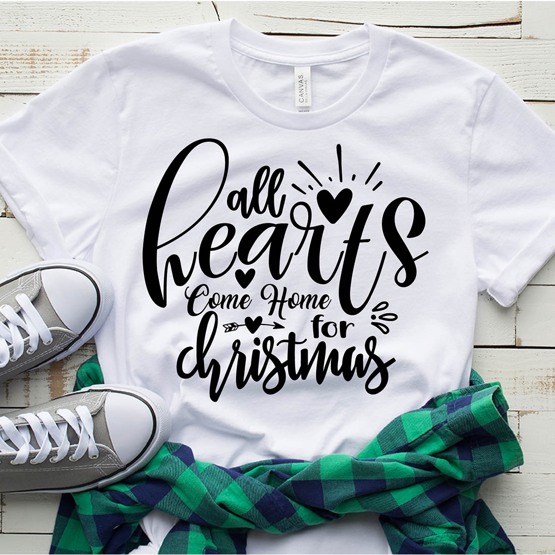 Image of a white t-shirt with a gorgeous black slogan "All Hearts Come Home For Christmas".